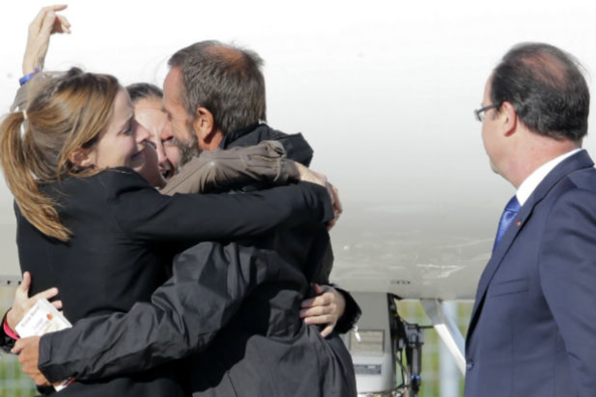 Former French hostage Daniel Larribe is welcomed by relatives as French President Francois Hollande looks on on the tarmac upon their arrival at Villacoublay military airport, near Paris, October 30, 2013 (Jacky Naegelen/Courtesy Reuters).