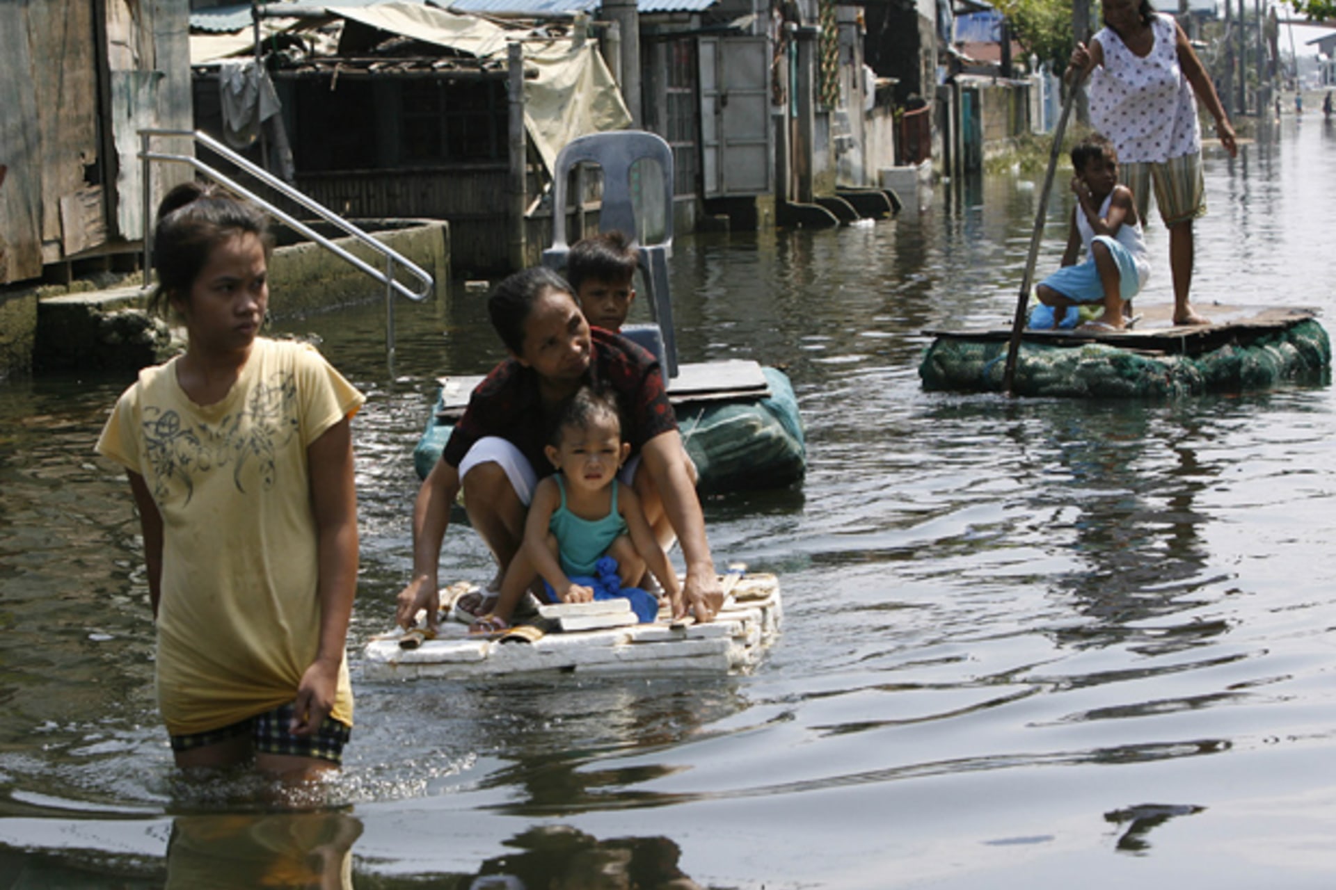 Residents use an improvised raft, made of styrofoam, to cross floodwaters at Dampalit town in Malabon city