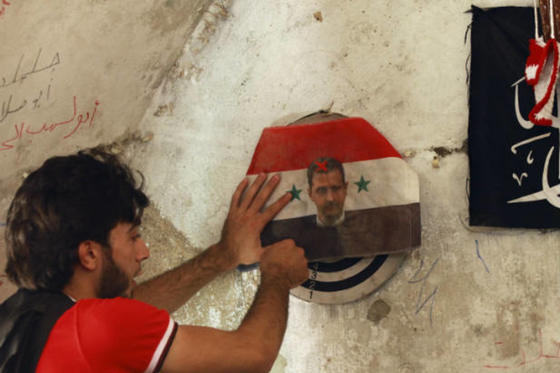 A member of the Free Syrian Army plays darts on a picture of Syrian President Bashar al-Assad in the Bab al-Nasr neighborhood of Aleppo June 28, 2013 (Khatib/Courtesy Reuters).