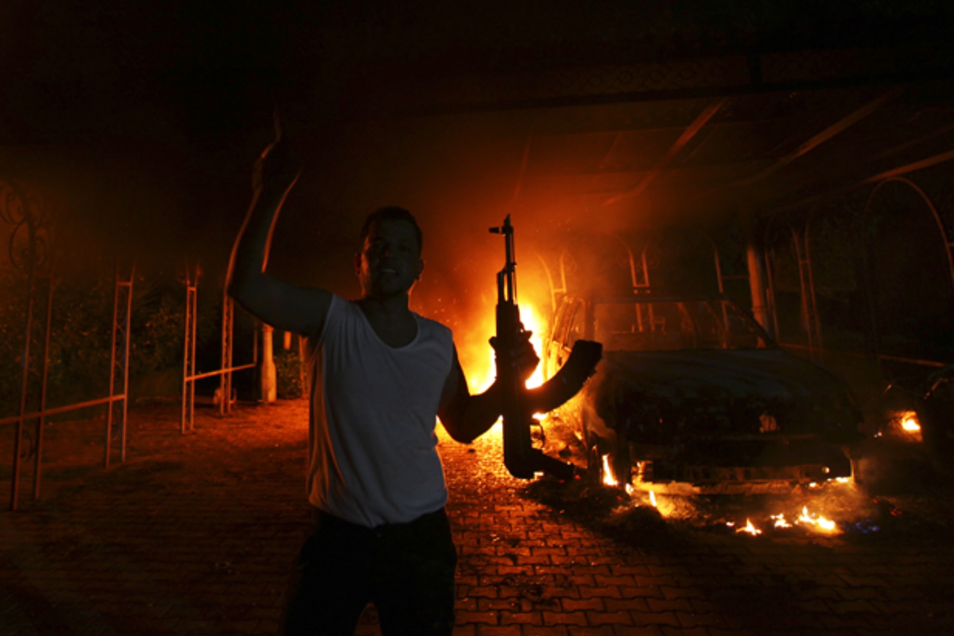 A protester reacts as the U.S. Consulate in Benghazi is seen in flames