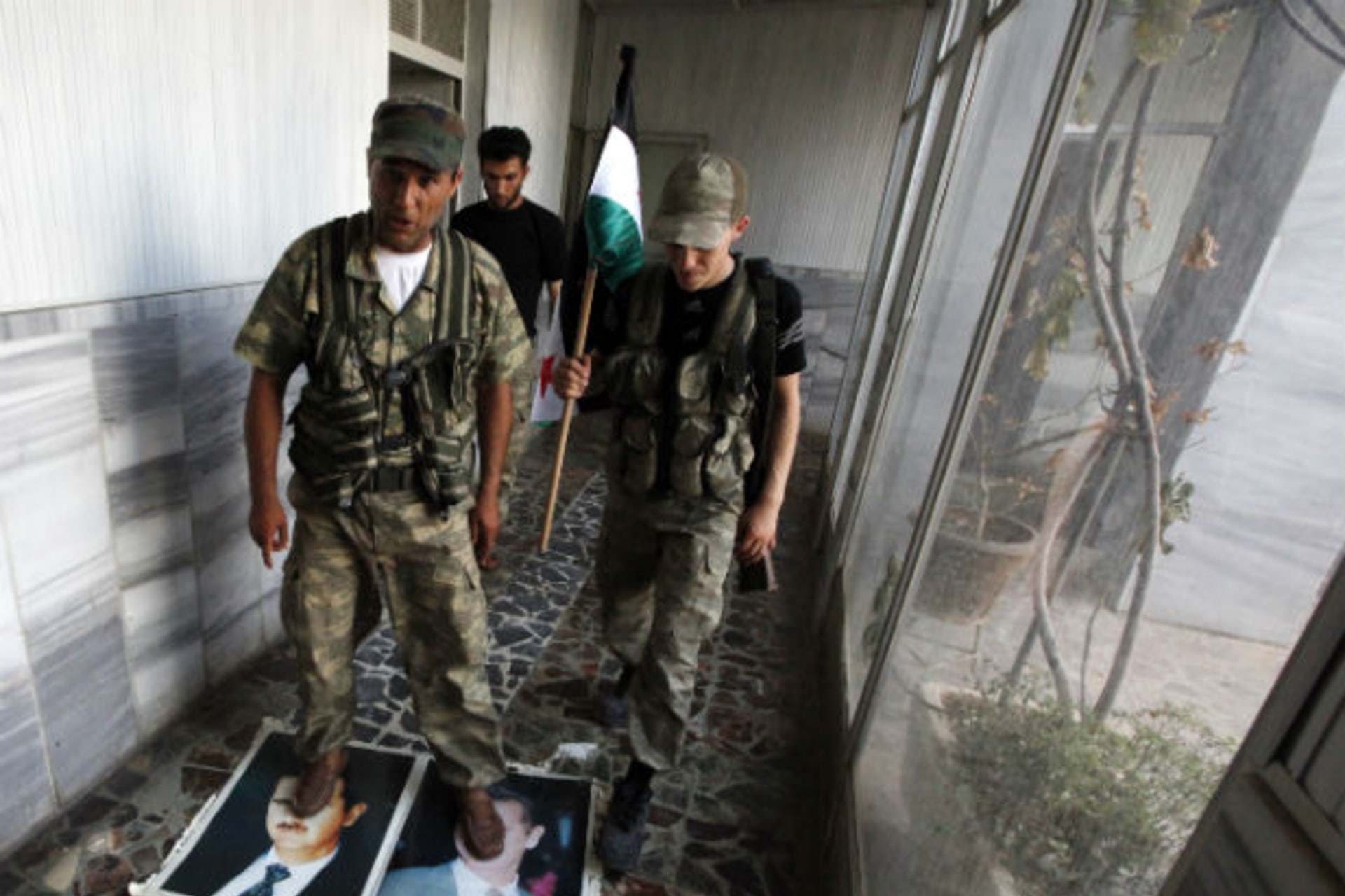 A Free Syrian Army soldier steps on portraits of President Bashar al-Assad at the Bab Al-Salam border crossing to Turkey on July 22, 2012 (Umit Bektas/Courtesy Reuters).