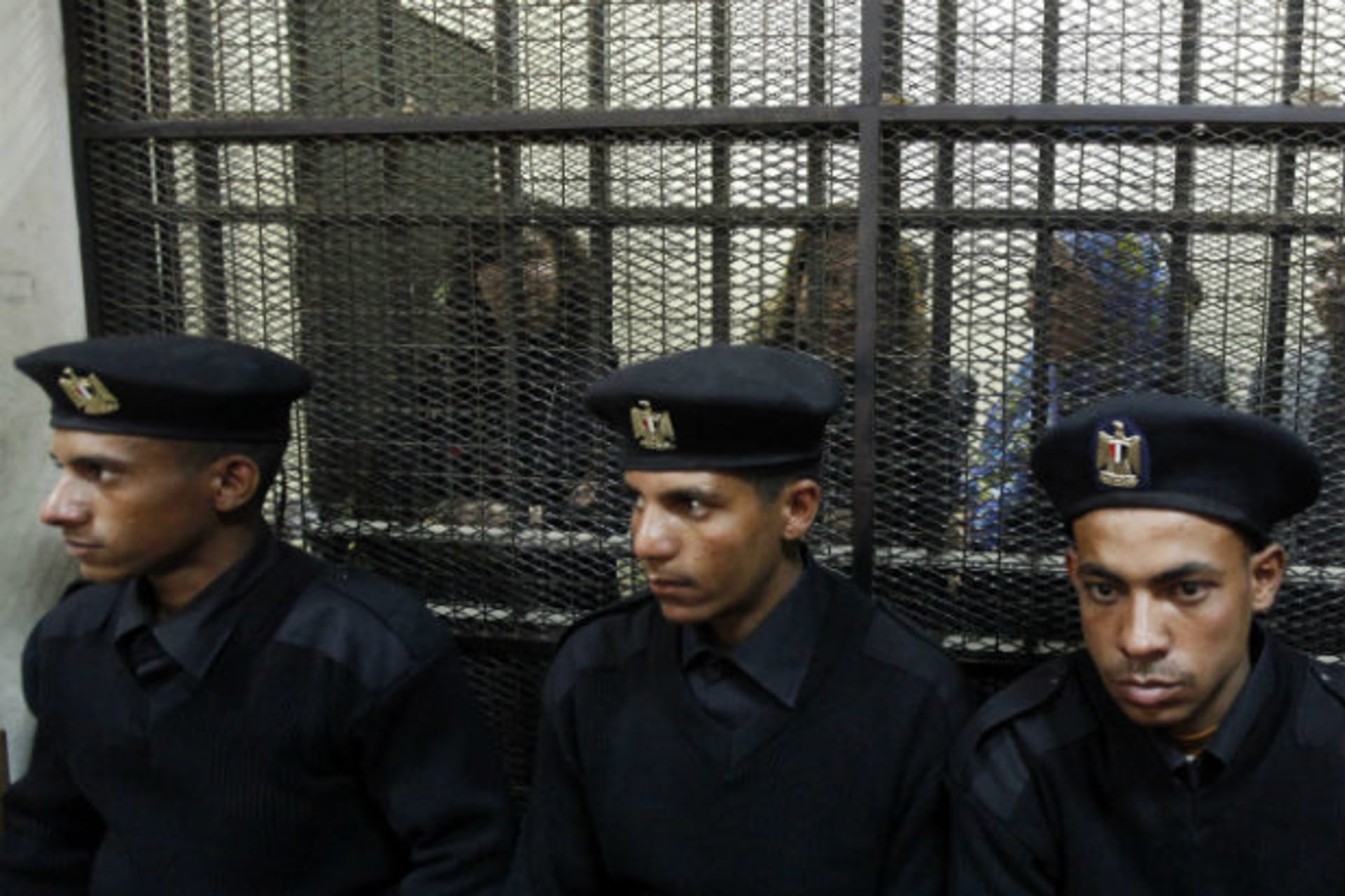 Some of the fourteen Egyptian activists who were accused of working for unlicensed non-governmental organizations and receiving illegal foreign funds, stand in a cage during the opening of their trial in Cairo on February 26, 2012 (Mohamed Abd