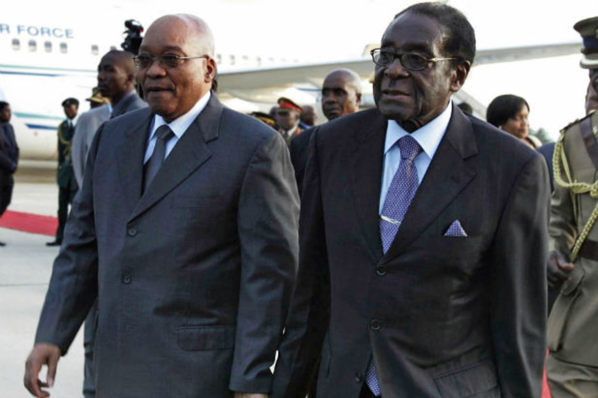 South African President Jacob Zuma (L) walks with Zimbabwean President Robert Mugabe at Harare International airport, March 16, 2010.