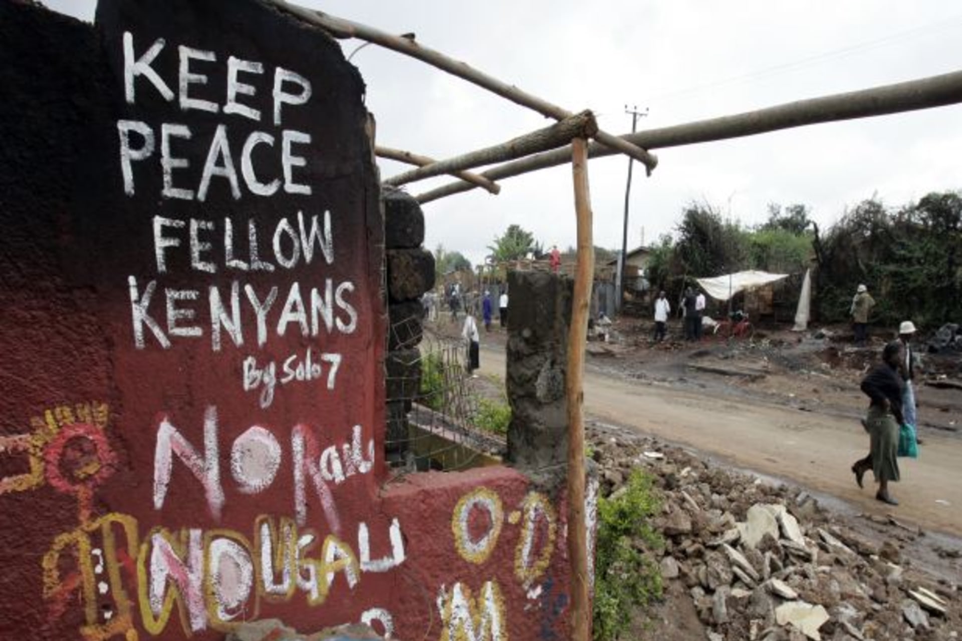 <p>Kenyans walk past a destroyed house in the sprawling Kibera slums, which was one of the most affected areas during the post-election violence in 2007 (Antony Njuguna/Courtesy Reuters).</p>
