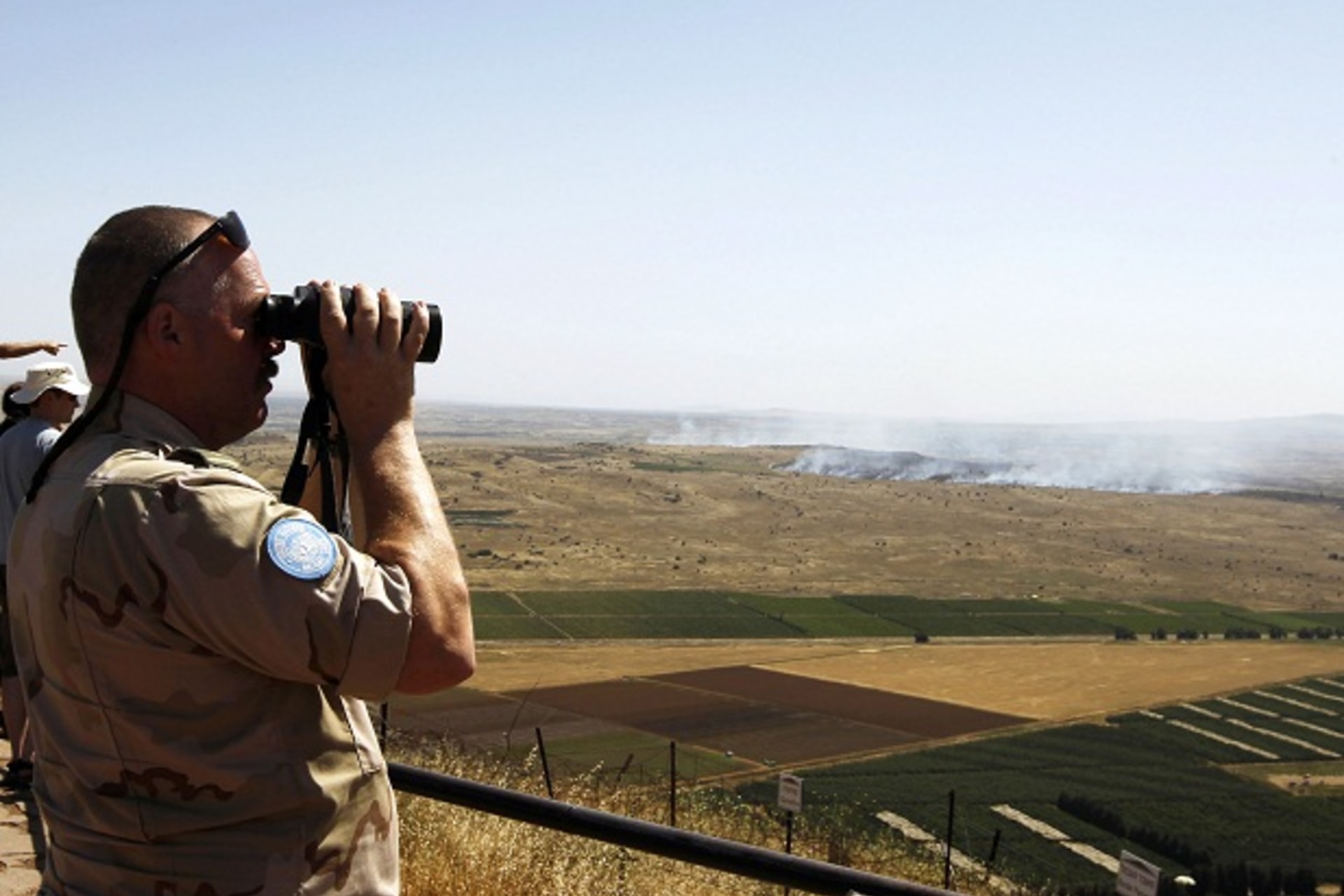 A U.N. peacekeeping soldier uses binoculars to watch fighting between forces loyal to Syrian regime and rebels opposed to Syrian President Assad, from Israeli-occupied Golan Heights