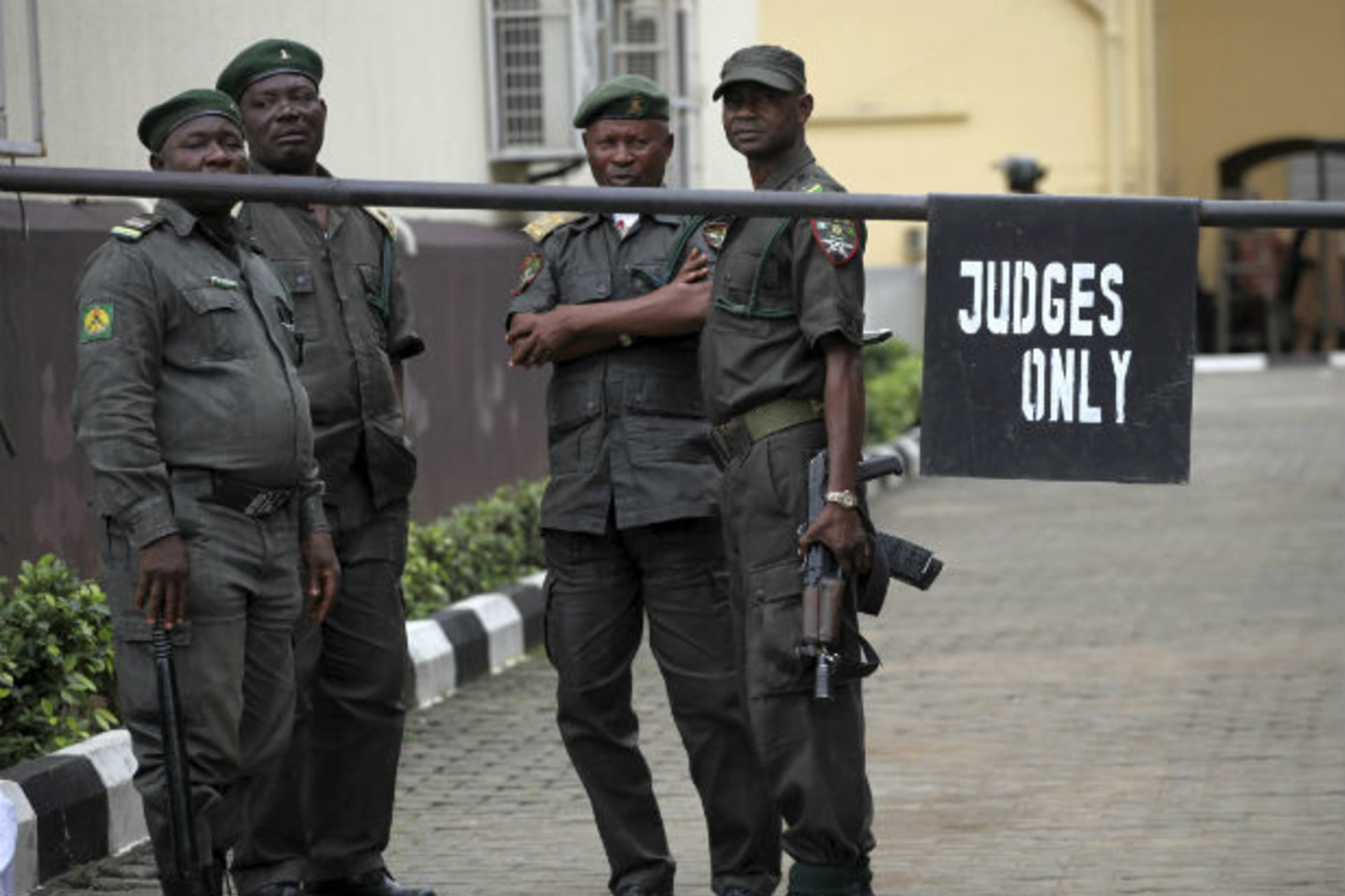 Prison officials wait outside the Lagos high court where Hamza Al-Mustapha is standing trial 04/08/2011.