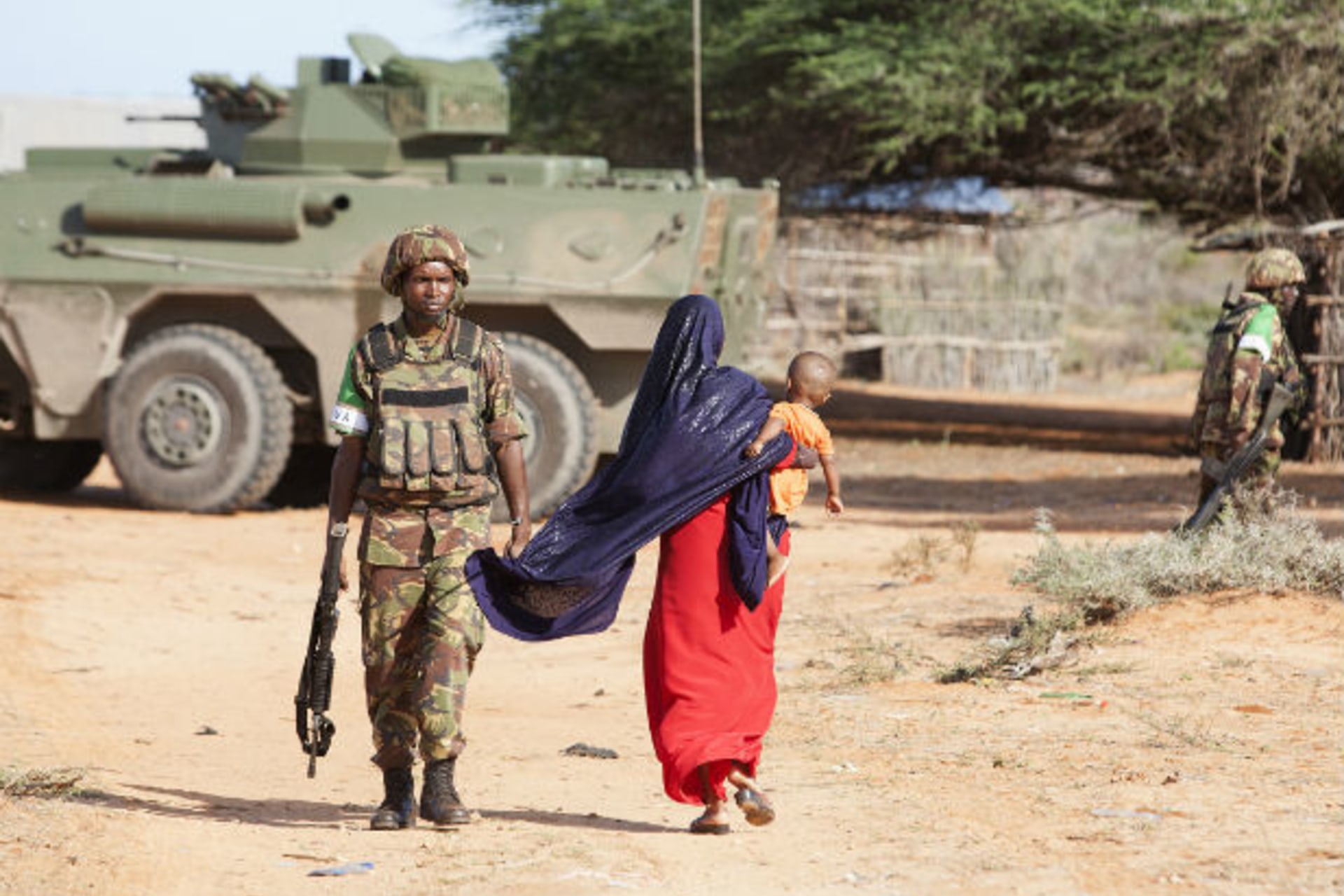 A woman walks by a Kenya Defence Force (KDF) soldier on the outer perimeter area of the Kismayu airport controlled by the African Mission in Somalia (AMISOM), November 11, 2013.