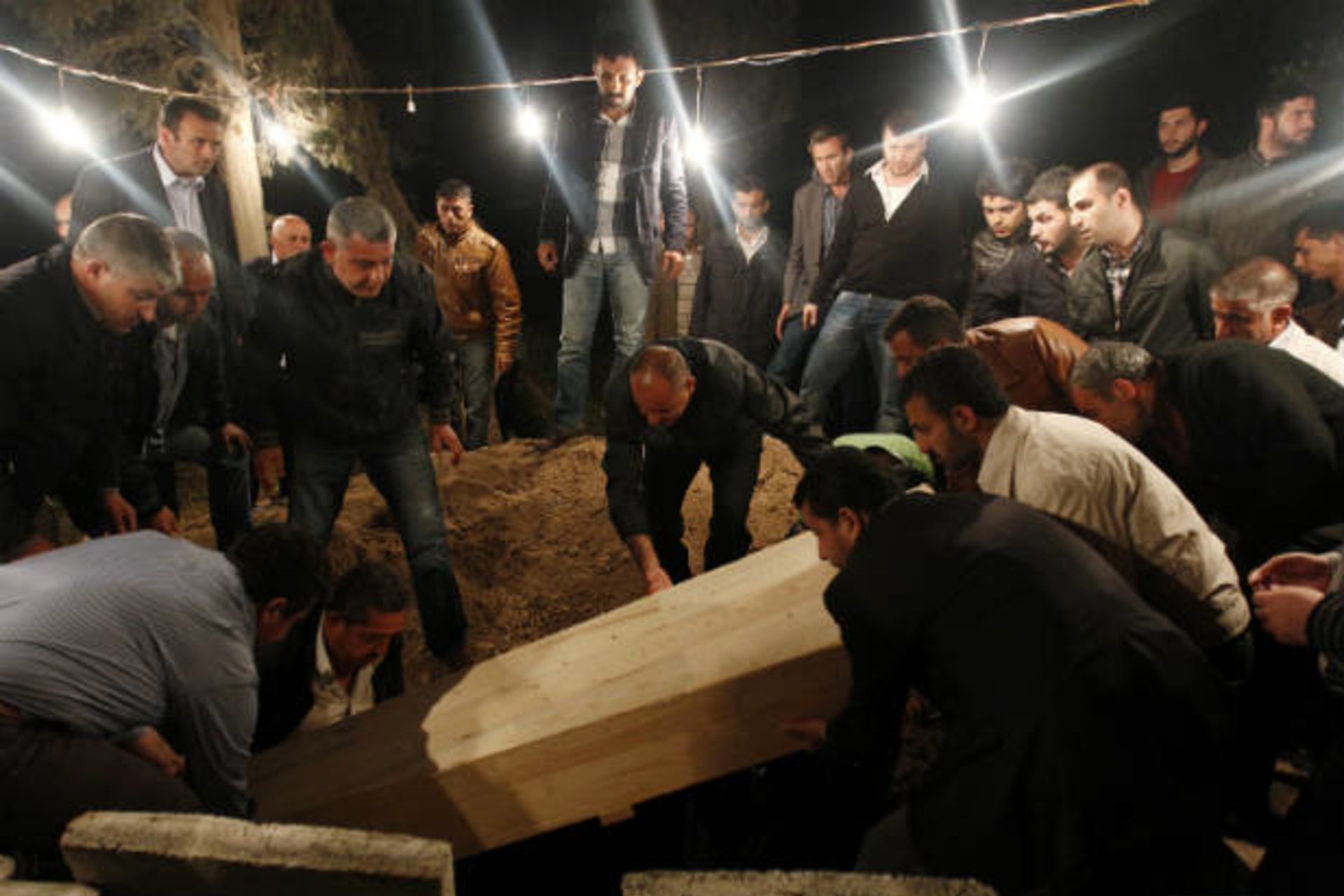Relatives of 55-year-old Kemal Baz, a victim of a car bomb attack, lower his coffin into a grave in the town of Reyhanli in Hatay province near the Turkish-Syrian border May 15, 2013 (Bektas/Courtesy Reuters)..