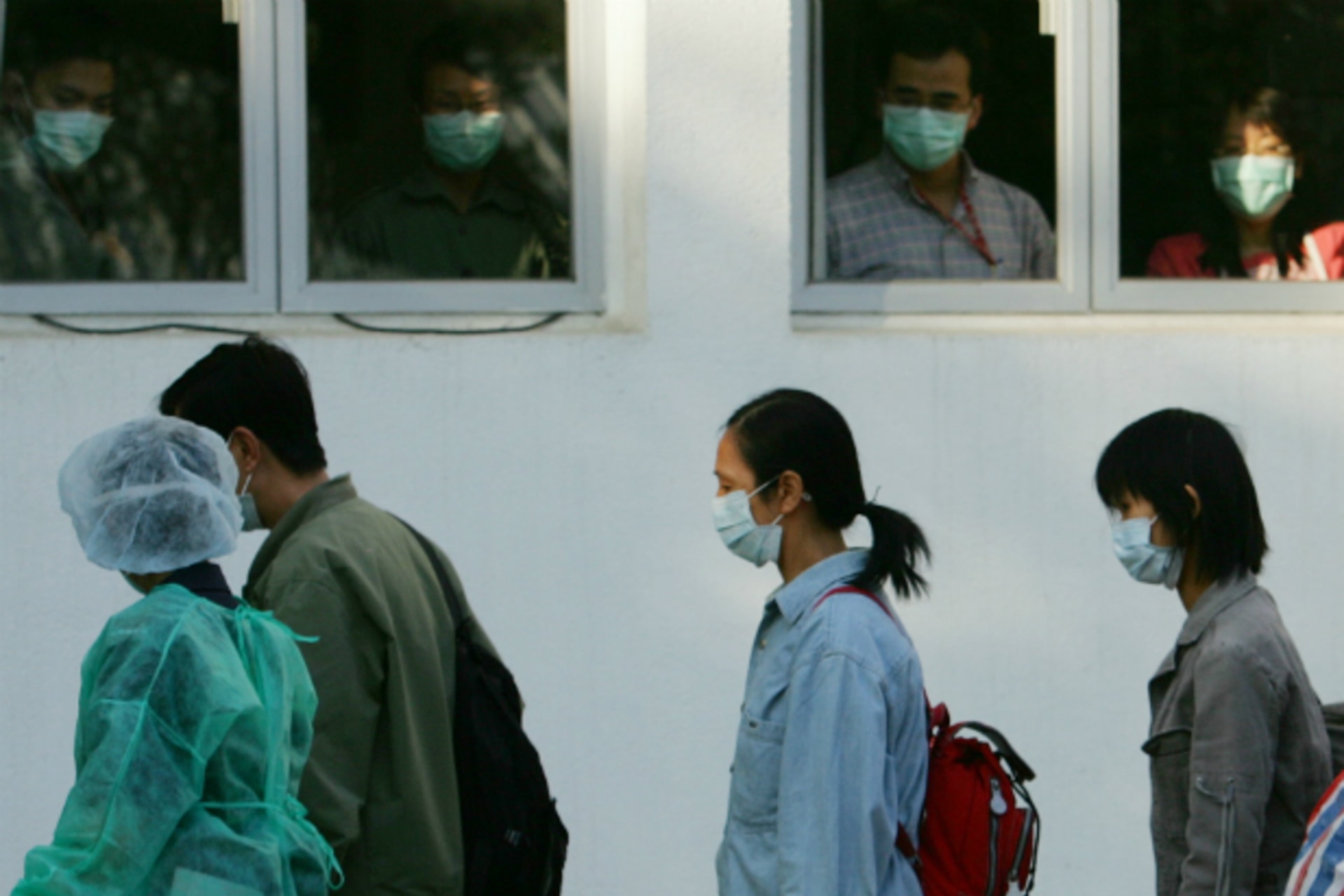 Observers look out of windows as "patients" walk past during a SARS outbreak drill in Hong Kong November 19, 2004.