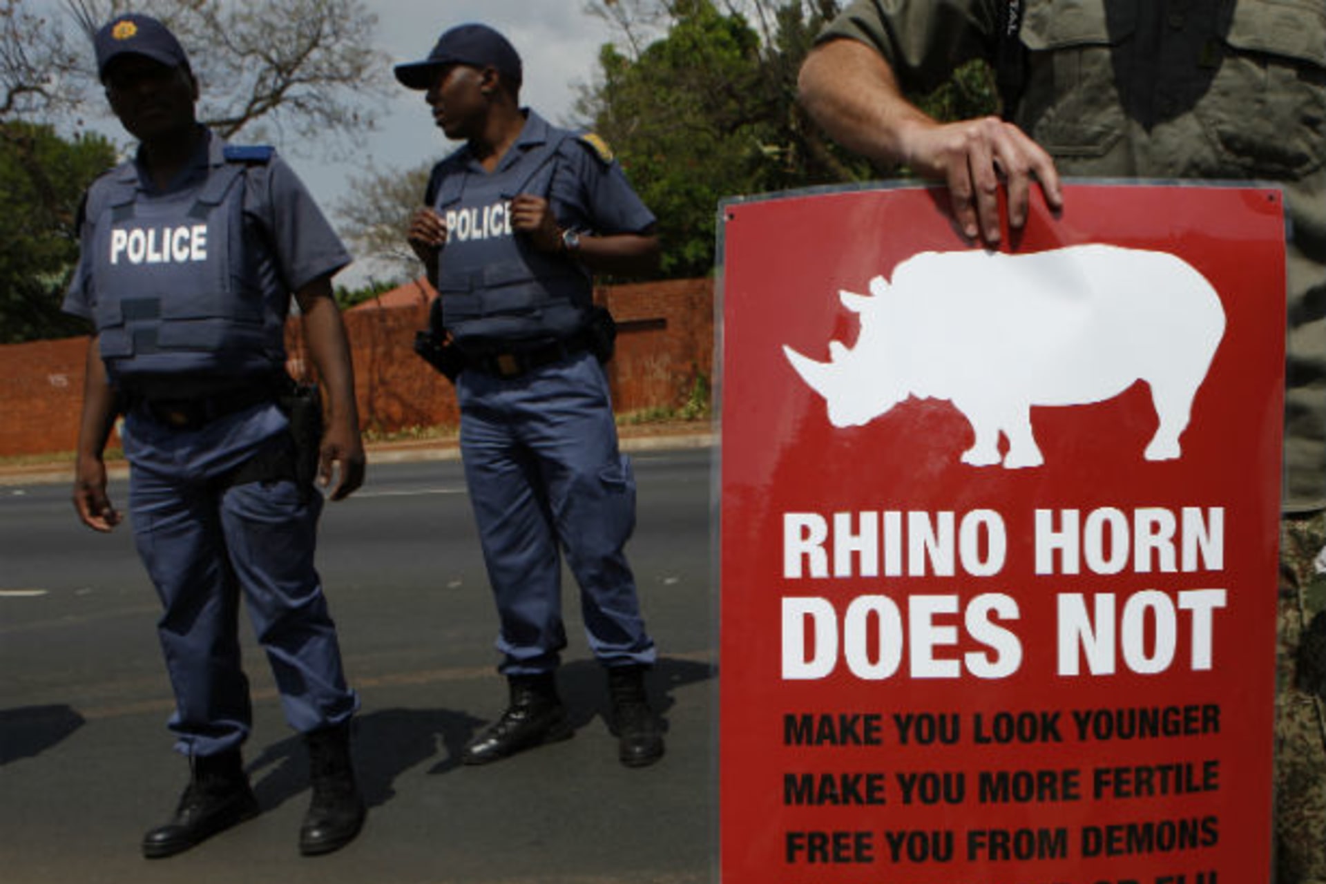 Policeman look on as a protester carries a placard calling for an end to rhino poaching, which threatens the survival of rhino species, outside the Chinese embassy in Pretoria September 22, 2011. (Siphiwe Sibeko/Courtesy Reuters)