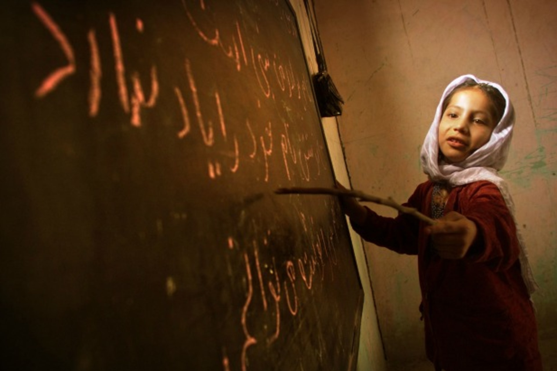 <p>A girl reads from the board in a home-based school in Kabul, Afghanistan, December 2001 (Courtsey Damir Sagolj/Reuters).</p>
