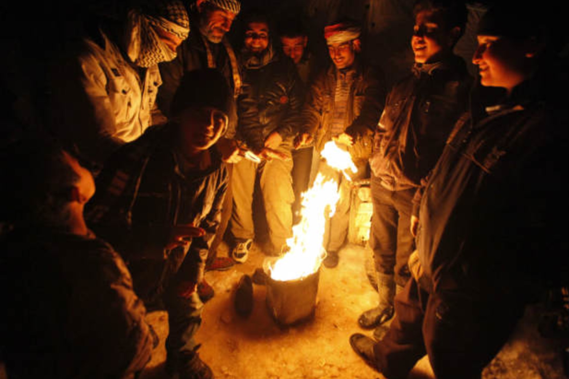 Syrian refugees from the town of Qara gather around a fire to keep themselves warm in a Syrian refugee camp on the Lebanese border town of Arsal, in eastern Bekaa Valley December 12, 2013 (Haju/Courtesy Reuters).