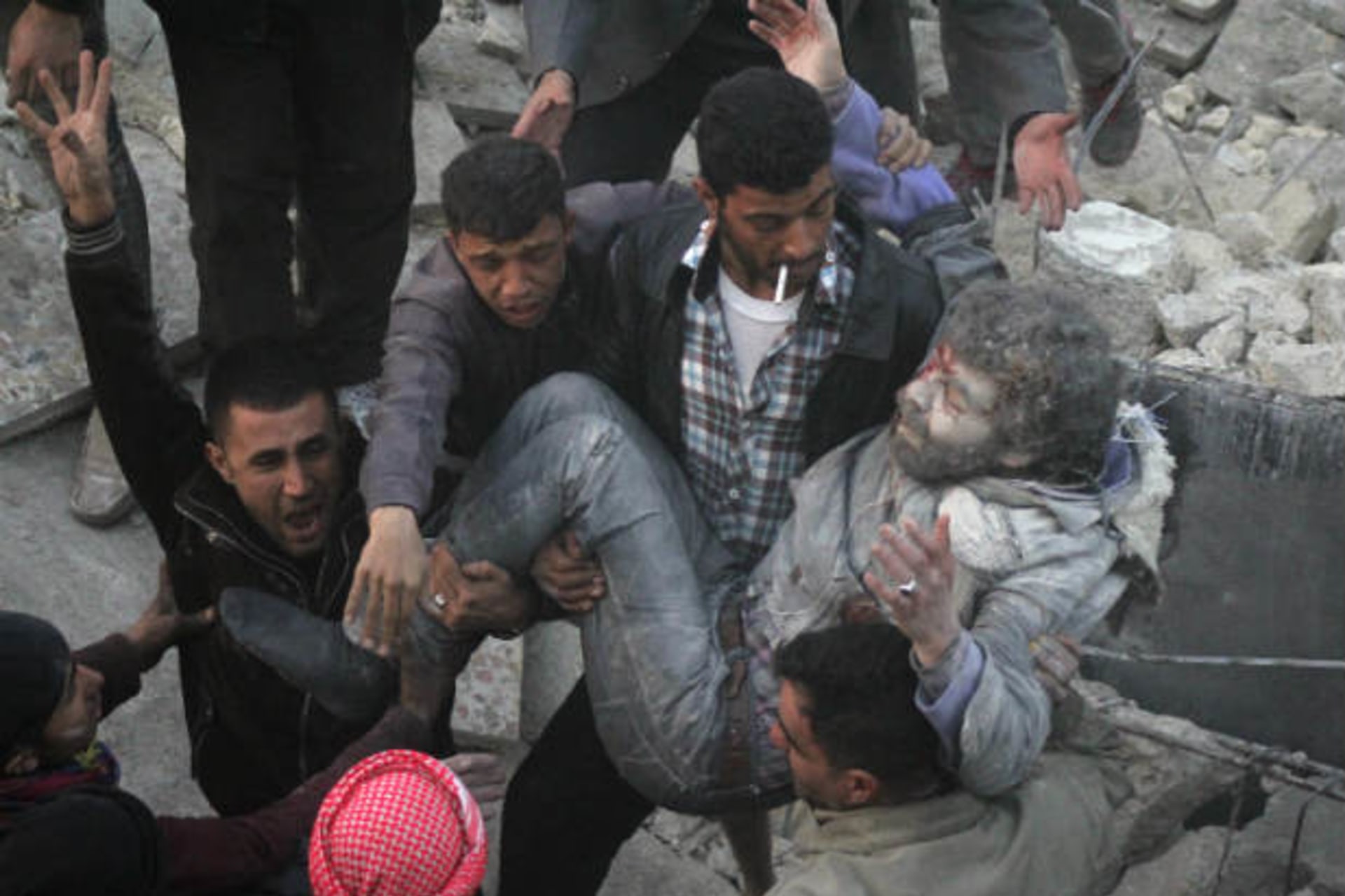 Residents react while calling for help as they hold an injured man that survived shelling after what activists said was an air strike from forces loyal to Syria's President Bashar al-Assad in Takeek Al-Bab area of Aleppo, December 17, 2013 (Abo