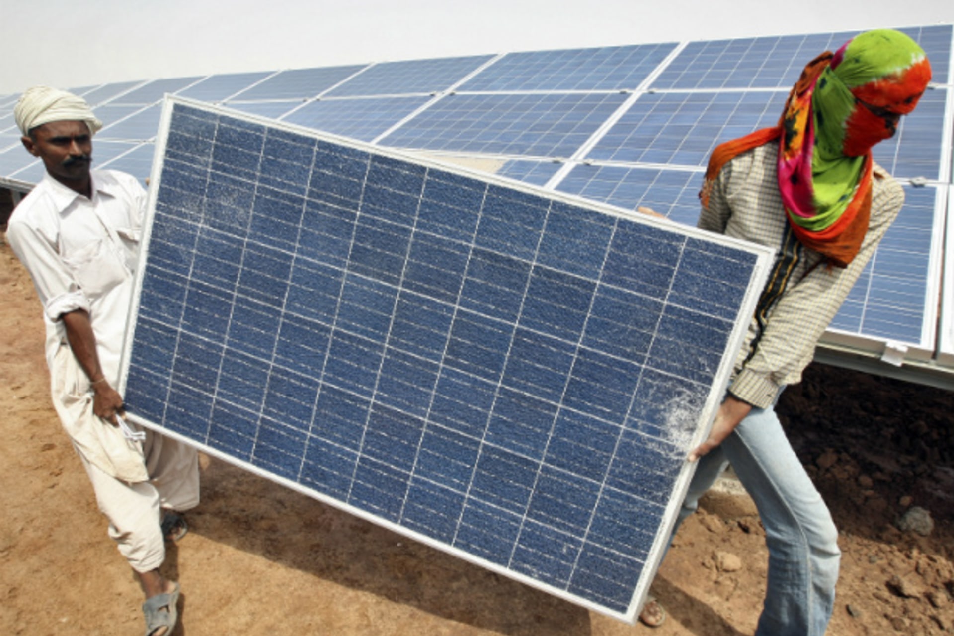 <p>Workers carry a damaged photovoltaic solar panel at the Gujarat solar park under construction in the Indian state of Gujarat (Reuters/Amit Dave).</p>

