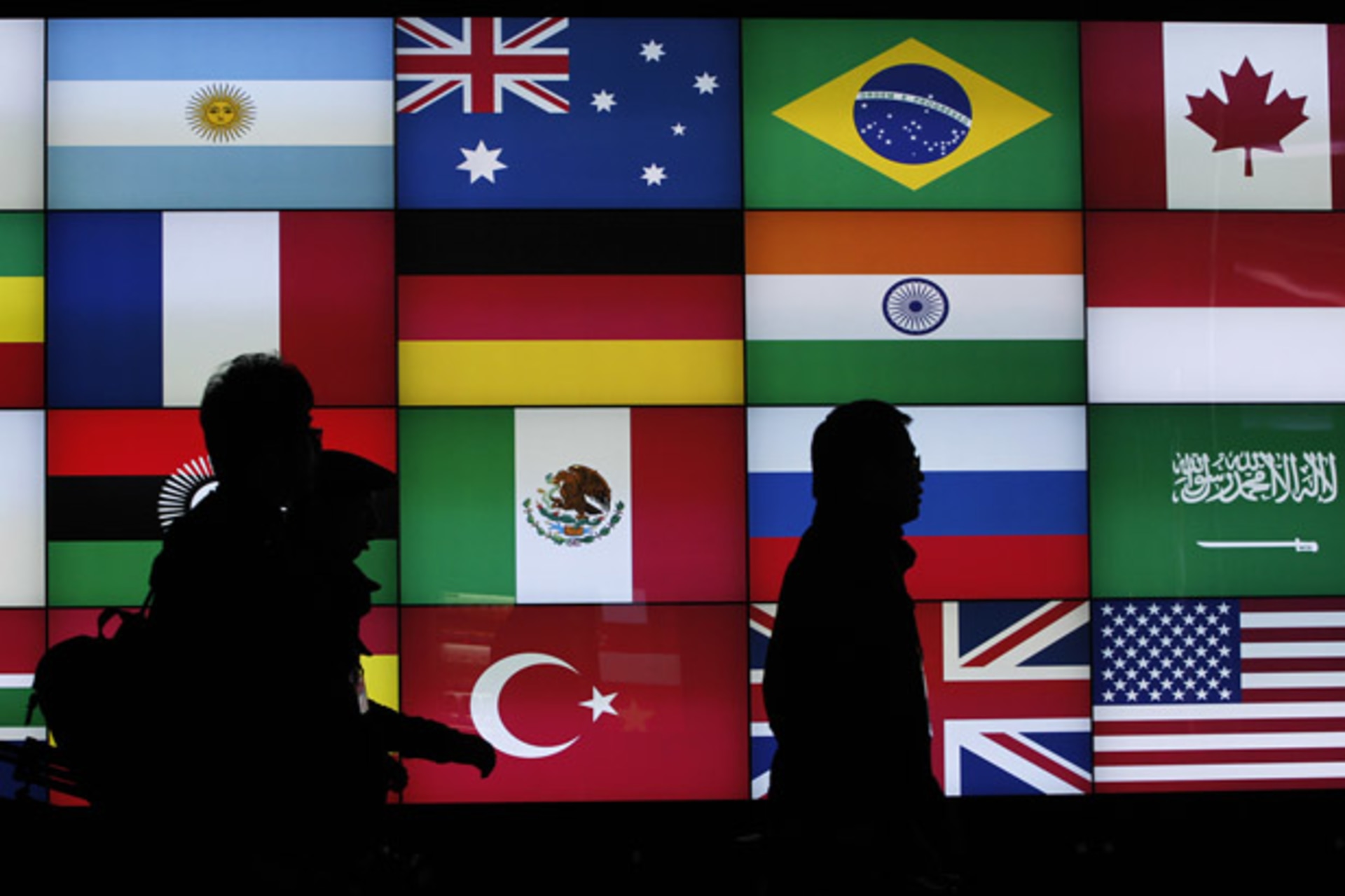 <p>Media workers walk past a screen showing flags of the participating countries during the G20 summit in Seoul, South Korea (Jo Yon-Hak/Courtesy Reuters).</p>
