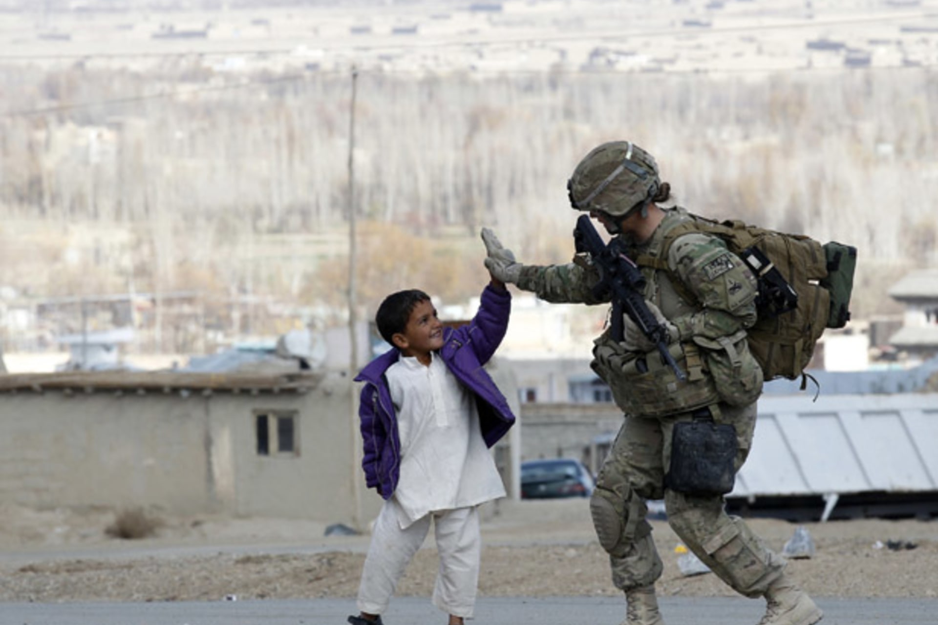 <p>A U.S. Army soldier high-fives with an Afghan boy during a patrol in eastern Afghanistan (Umit Bektas/ Courtesy Reuters).</p>