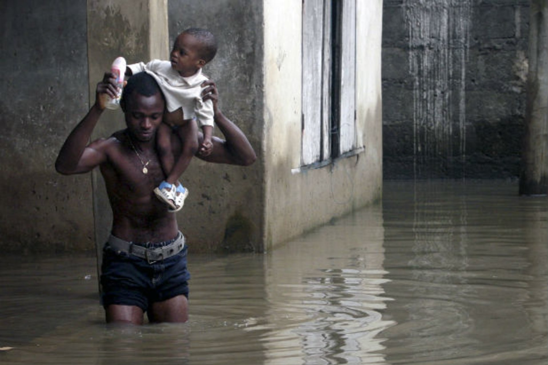 A man carries a child as he wades through flood waters in Ikorodu neighbourhood of Nigeria's main city of Lagos 05/08/2007.