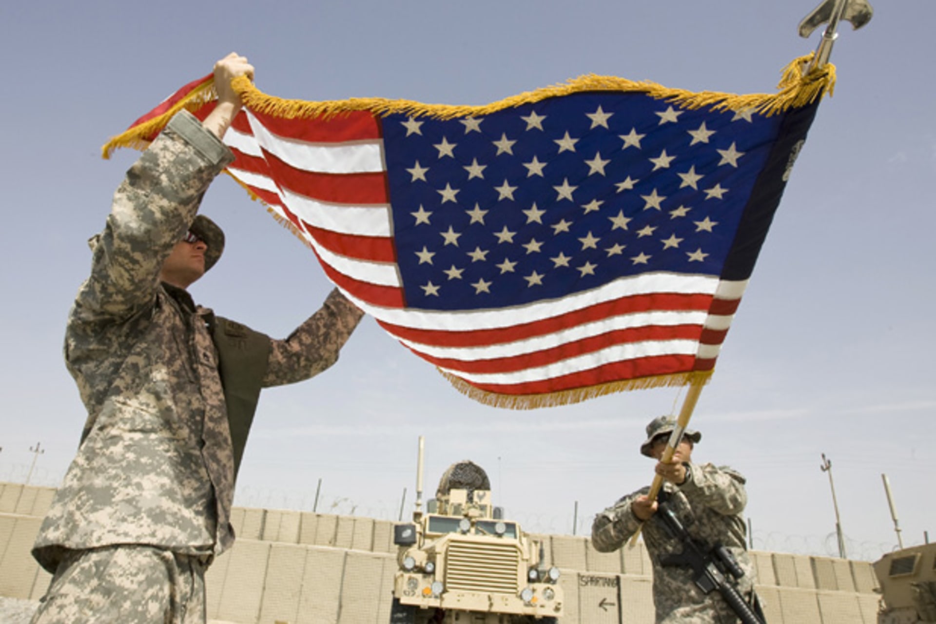 <p>U.S. Army soldiers roll up a national flag after their headquarters’ change of command ceremony in Afghanistan in 2010. (Shamil Zhumatov/ courtesy Reuters)</p>