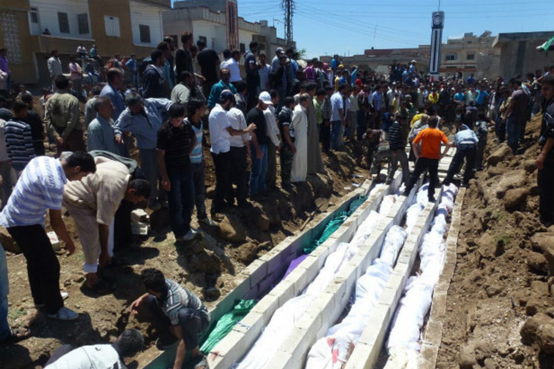 <p>People gather around a mass burial for victims purportedly killed at the massacre in the Syrian village of Houla on May 25. (Courtesy Reuters)</p>