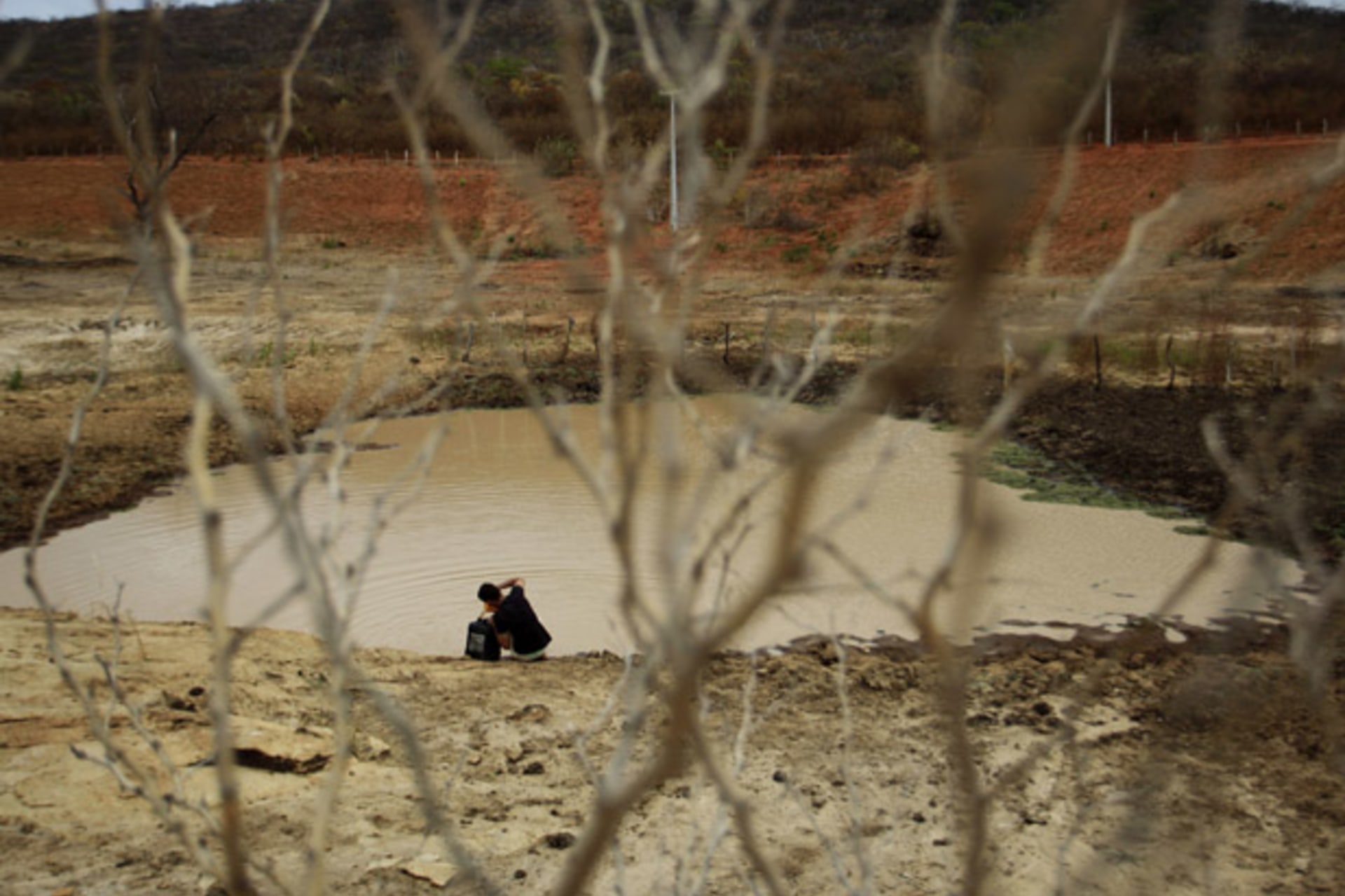 Geovani Santos collects water from a weir which has nearly dried up as a consequence of the drought in Maracas