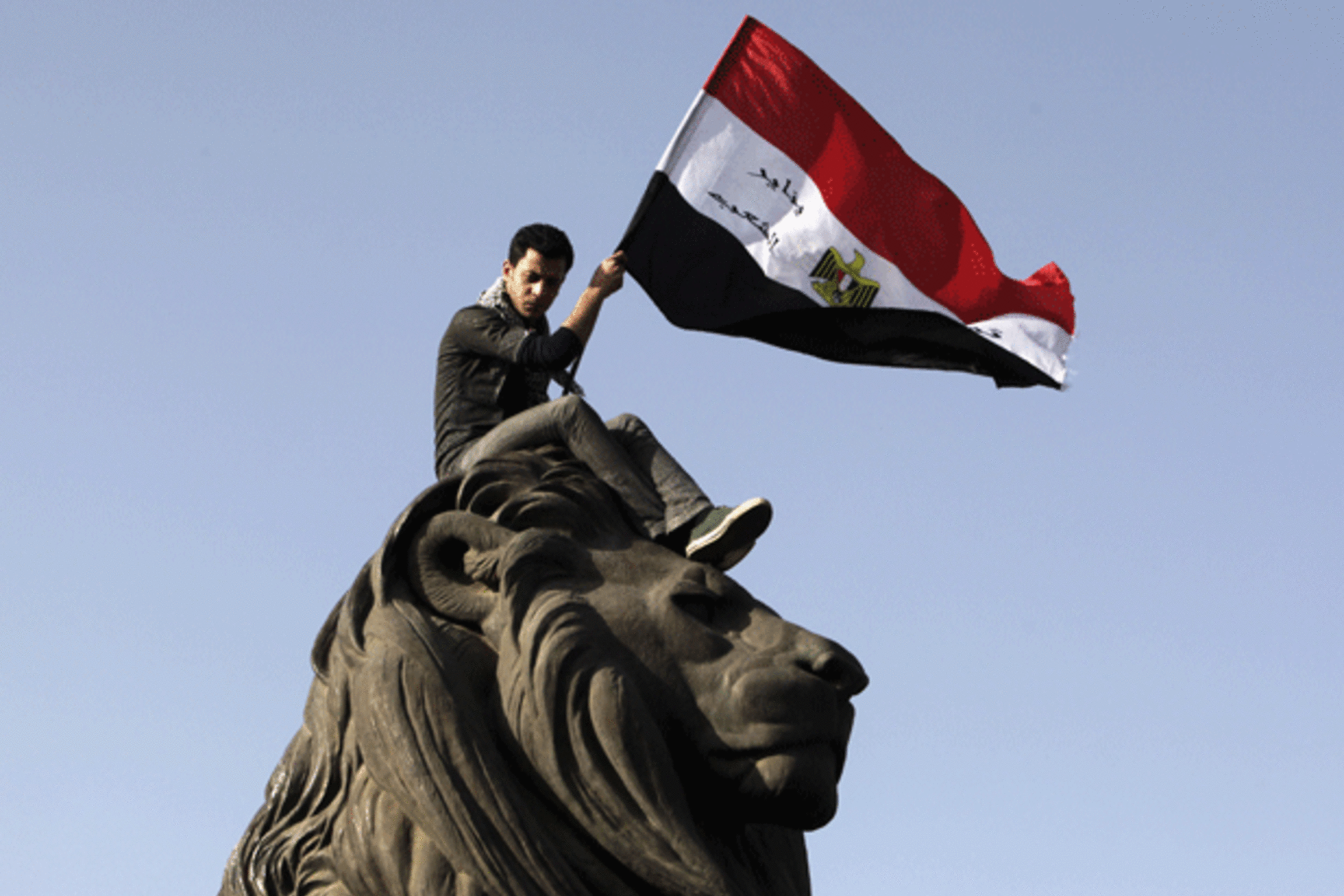 <p>A demonstrator carries an Egyptian flag near Tahrir square where demonstrators gathered to mark the first anniversary of Egypt’s uprising on January 25, 2012. (Asmaa Waguih/courtesy Reuters)</p>
