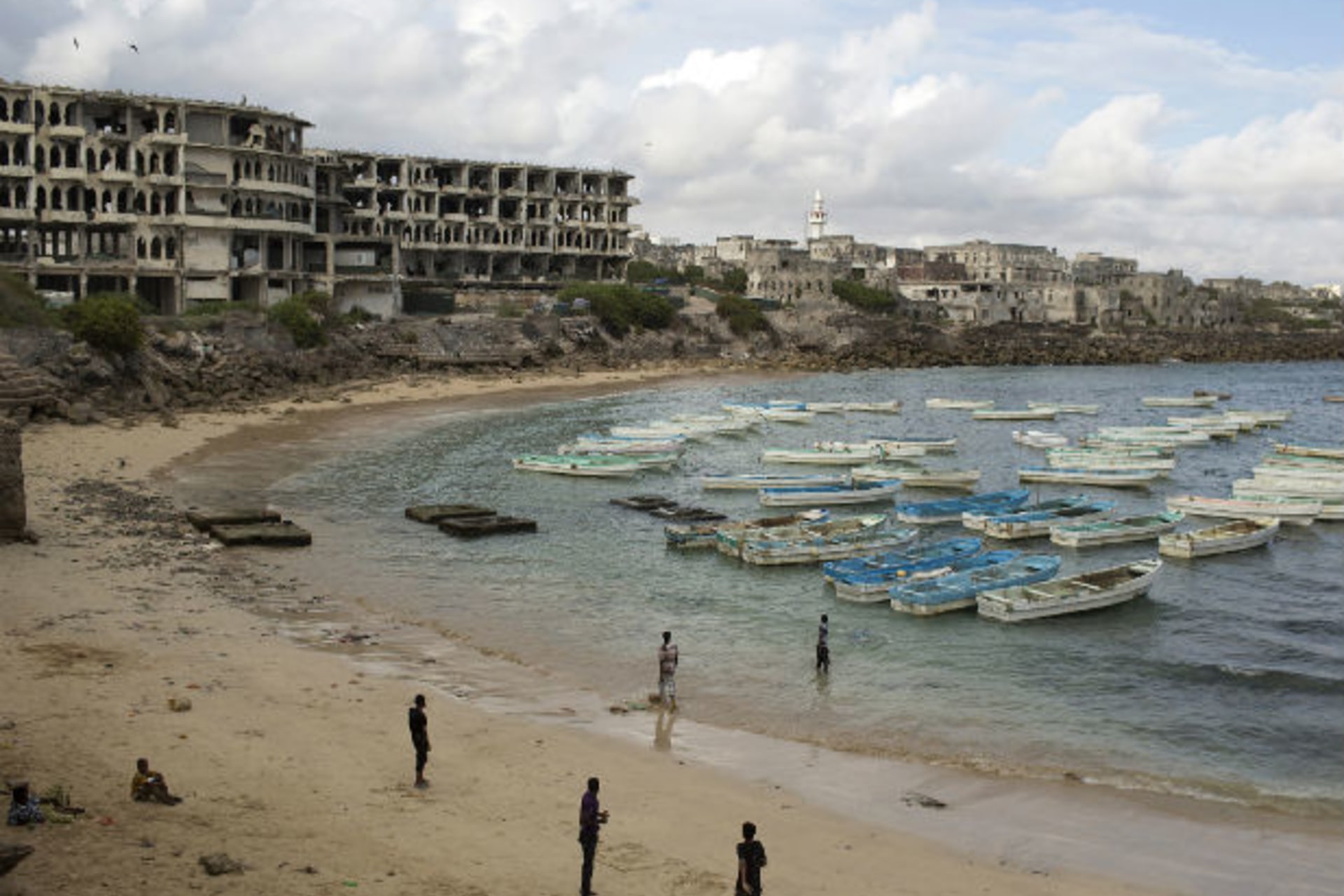 People stand and walk at a beach in the old port of Mogadishu November 13, 2013.