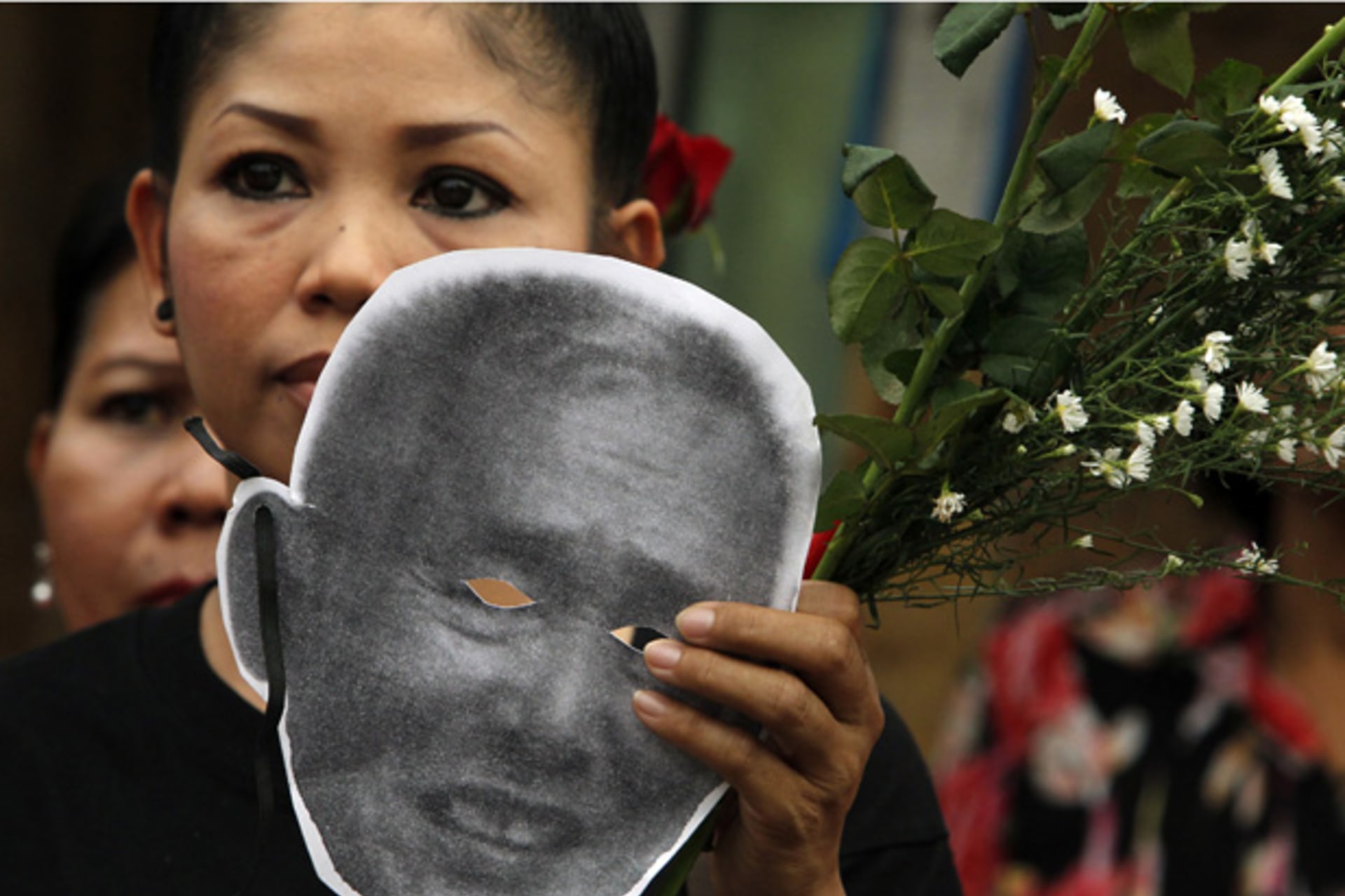 <p>An activist holds a cut-out mask of Amphon Tangnoppaku outside Bangkok Remand Prison.</p>
