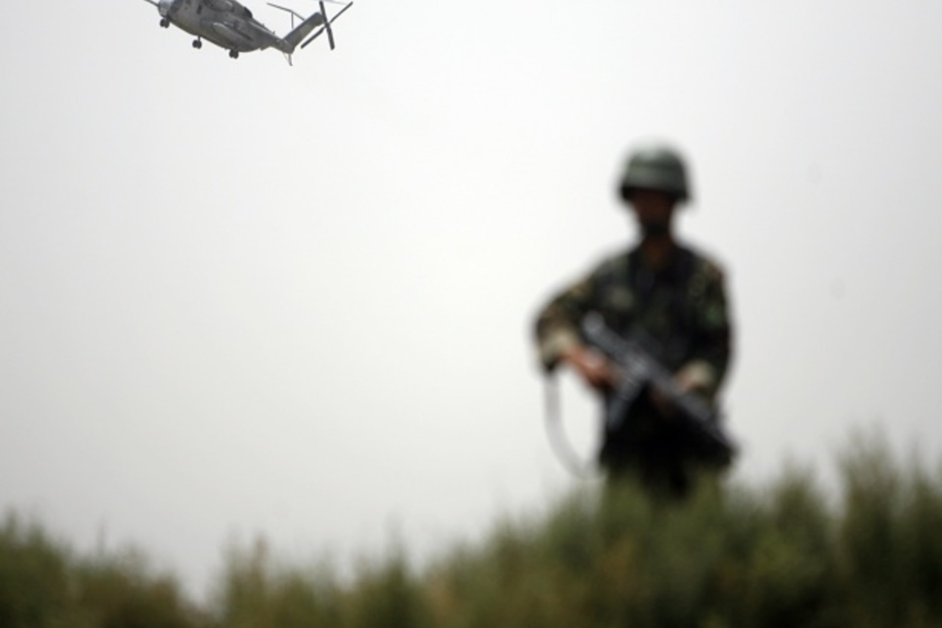 <p>An Afghan National army soldier keeps watch as a U.S. helicopter flies overhead in Khan Neshin district of Helmand province (Courtesy Reuters/Ahmad Masood).</p>

