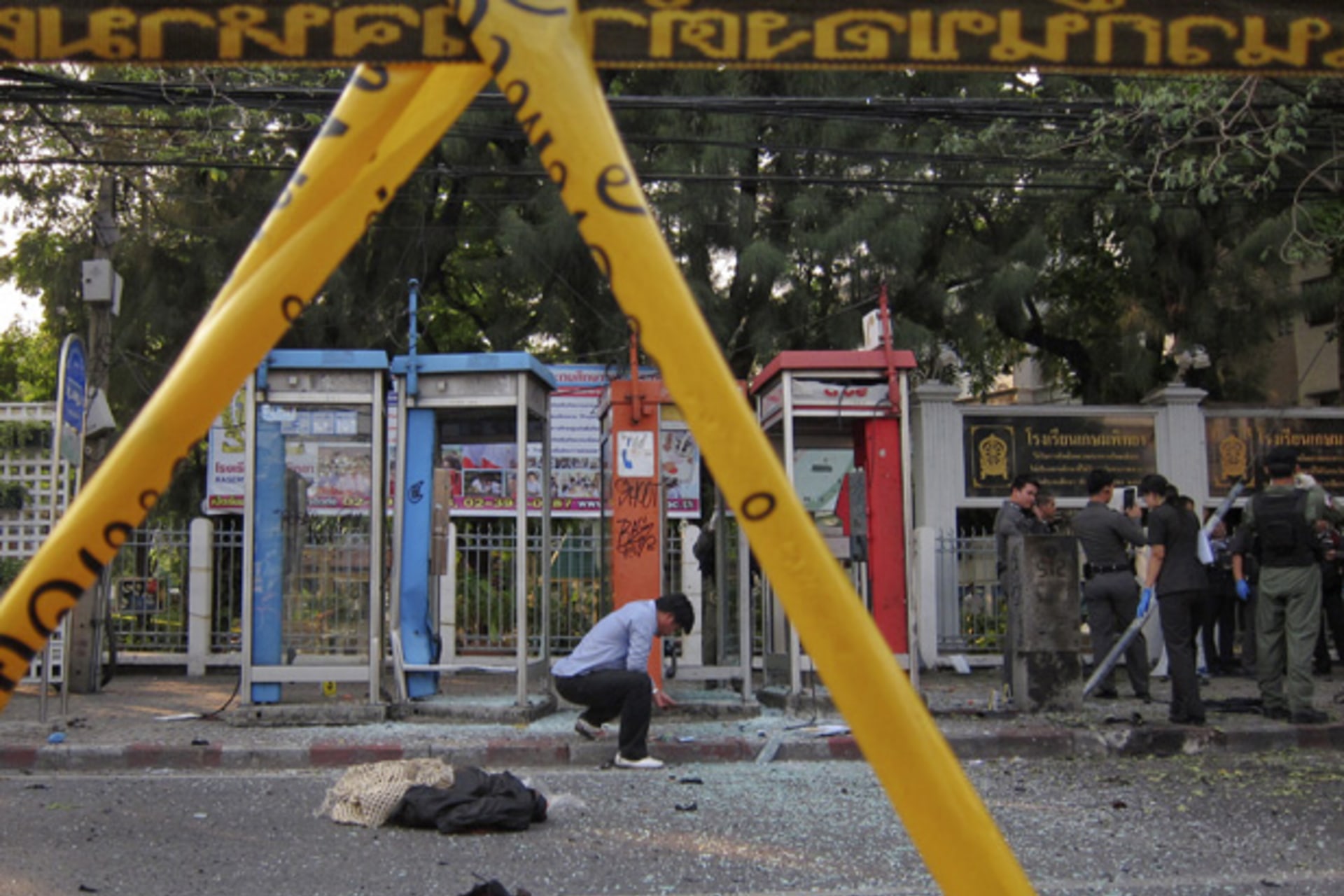 <p>Police and forensic experts investigate the site where a man was injured when a bomb he was carrying exploded, in central Bangkok February 14, 2012.</p>