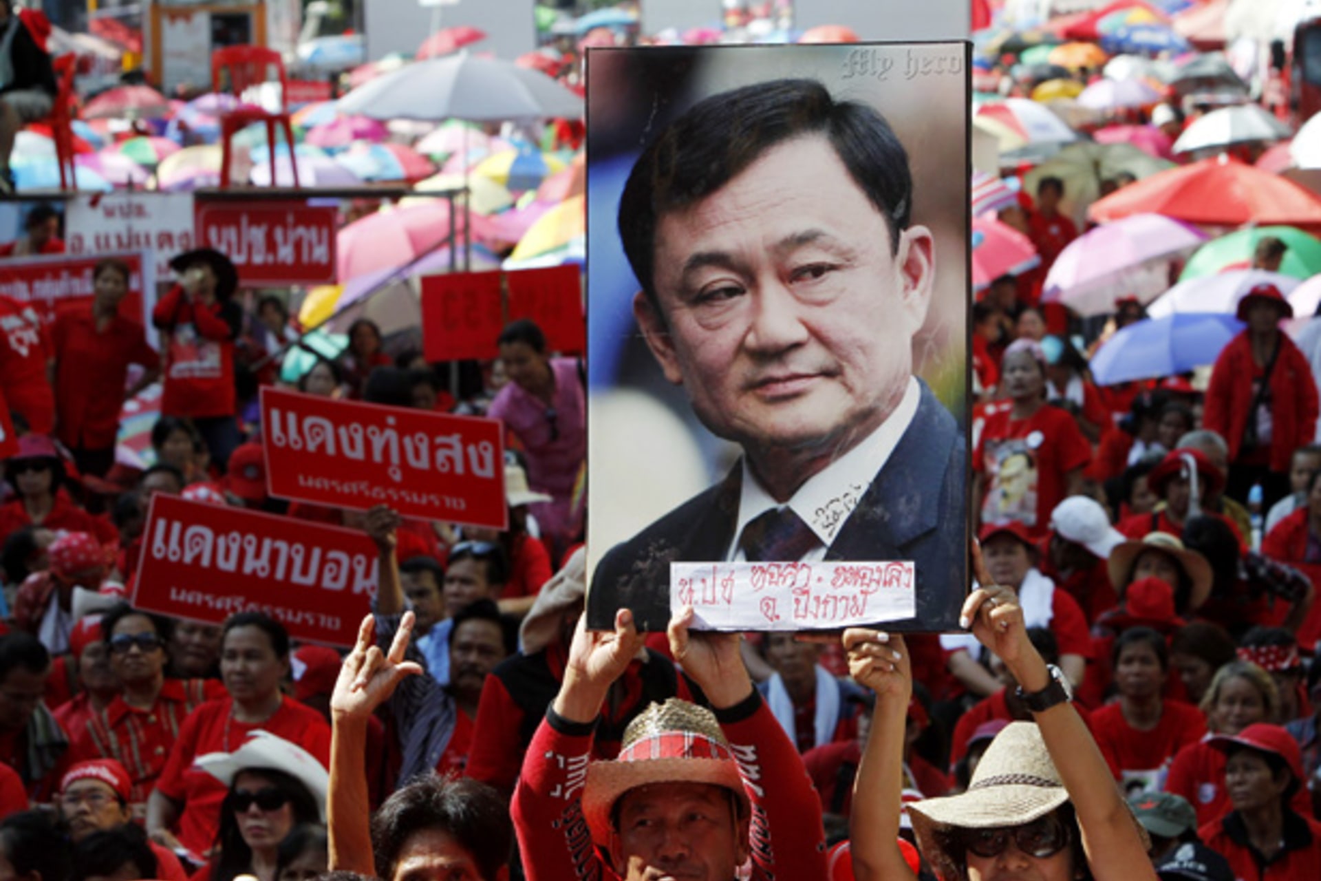 <p>Red shirt protesters hold a picture of former prime minister Thaksin Shinawatra at a gathering to mark the second anniversary of a government crackdown on red shirt protestors in Bangkok May 19, 2012.</p>

