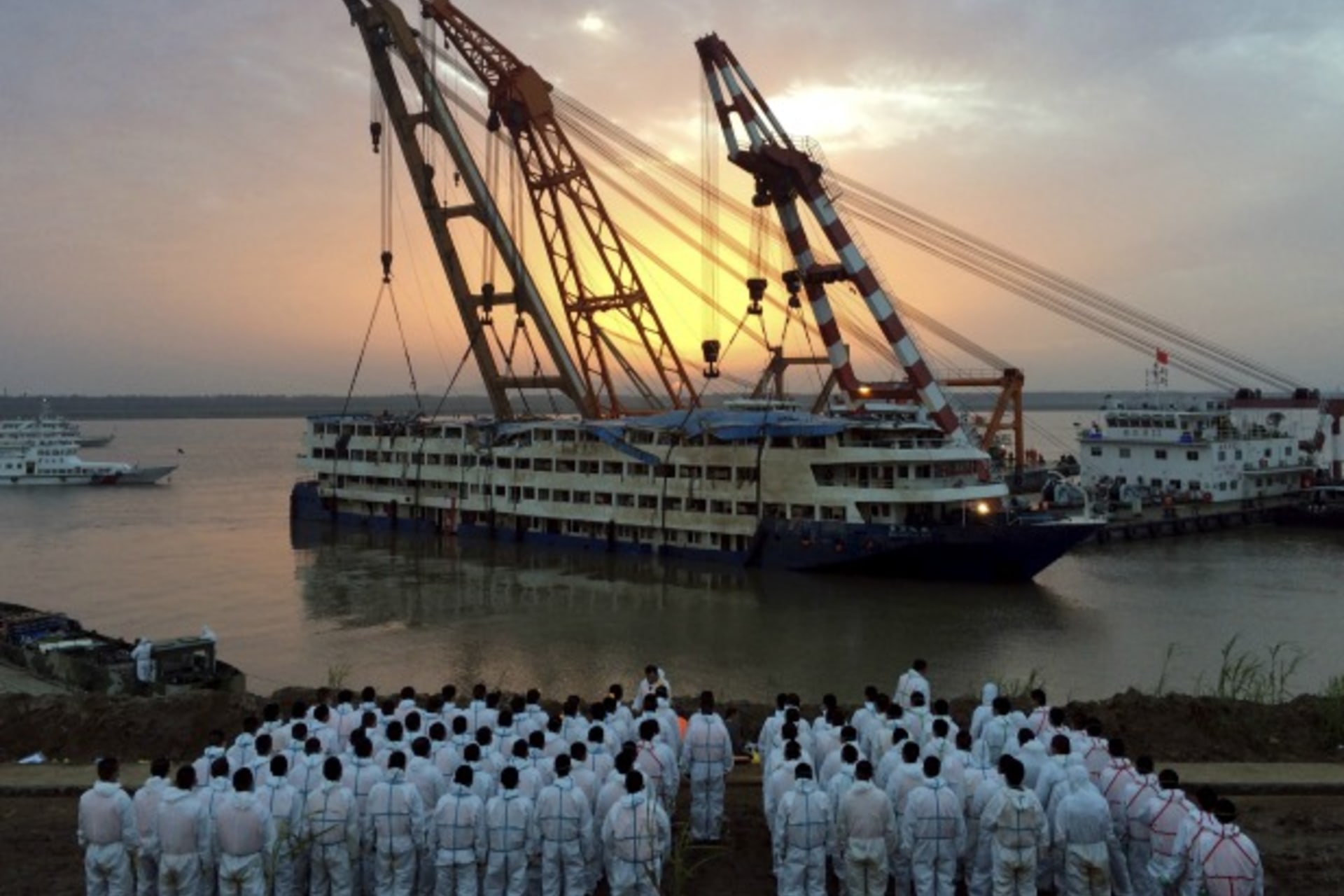 <p>Rescue workers stand on the river bank as the capsized cruise ship Eastern Star is pulled out of the Yangtze against sunset, i…rying 456 overturned in a freak tornado on Monday night. A total of 103 bodies have been found. REUTERS/China Daily CHINA OUT.</p>

