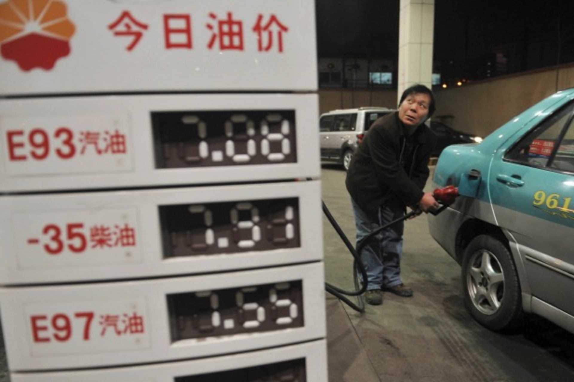 <p>A taxi driver looks at the price as he fills the tank of his car near a board showing recently increased prices at a gas station in Shenyang, Liaoning province, on February 20, 2011. (Stringer/Courtesy Reuters)</p>
