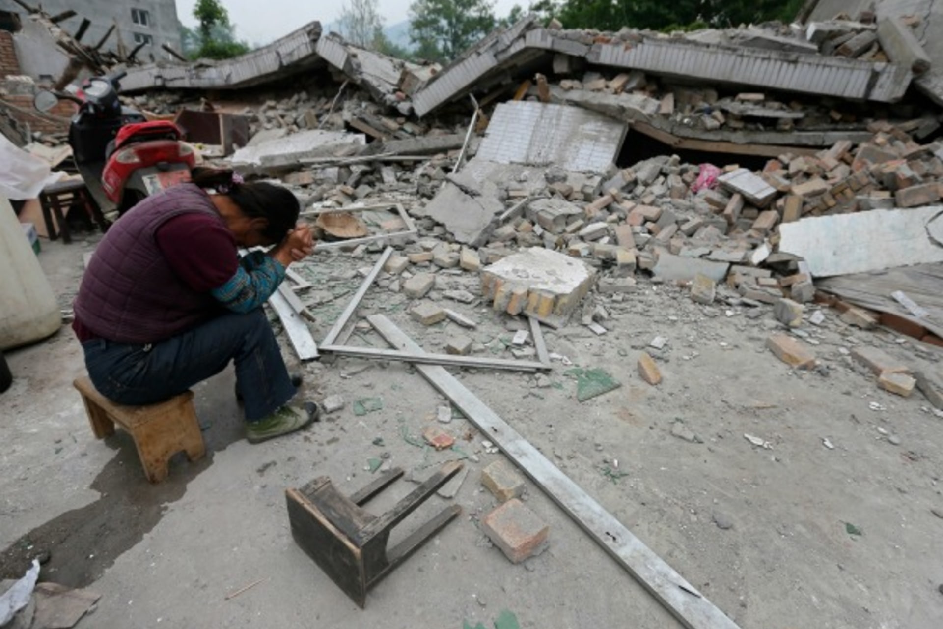 <p>A woman sits with her head down next to a damaged house after Saturday’s earthquake hit Lushan county, Ya’an, Sichuan province, on April 22, 2013.</p>
