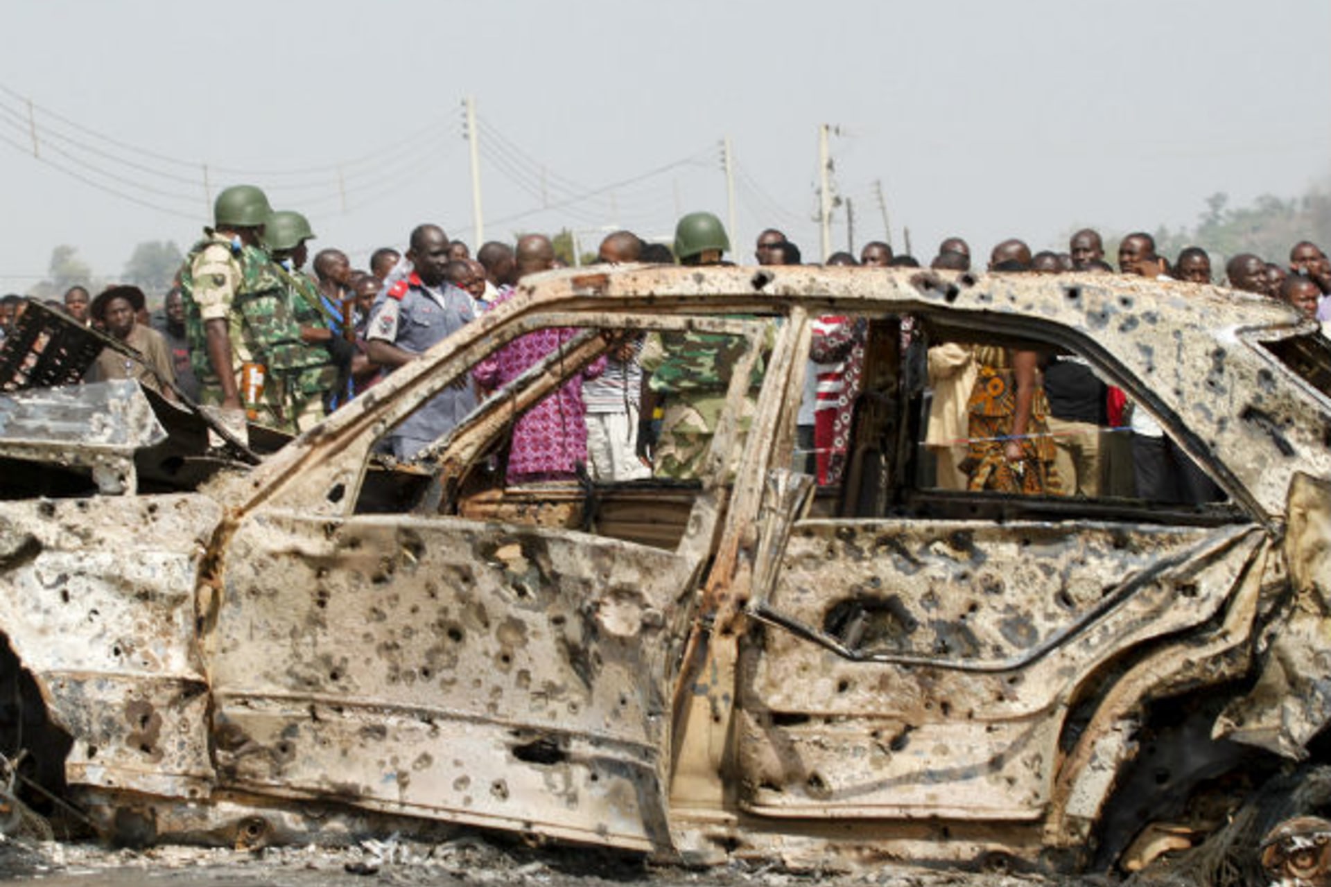 A crowd gathers near a car damaged by an explosion at St. Theresa Catholic Church at Madalla, Suleja, just outside Nigeria's capital Abuja, December 25, 2011.