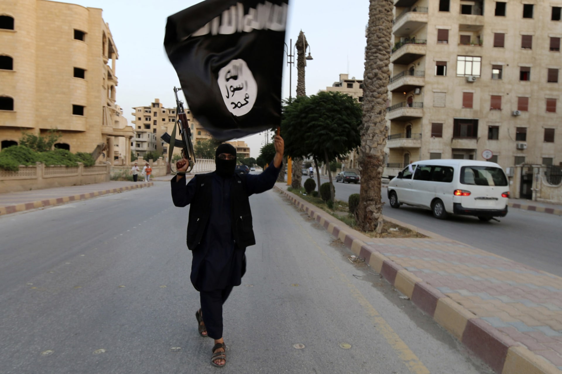 <p>A member loyal to the Islamic State in Iraq and the Levant (ISIL) waves an ISIL flag in Raqqa on June 29, 2014.</p>

