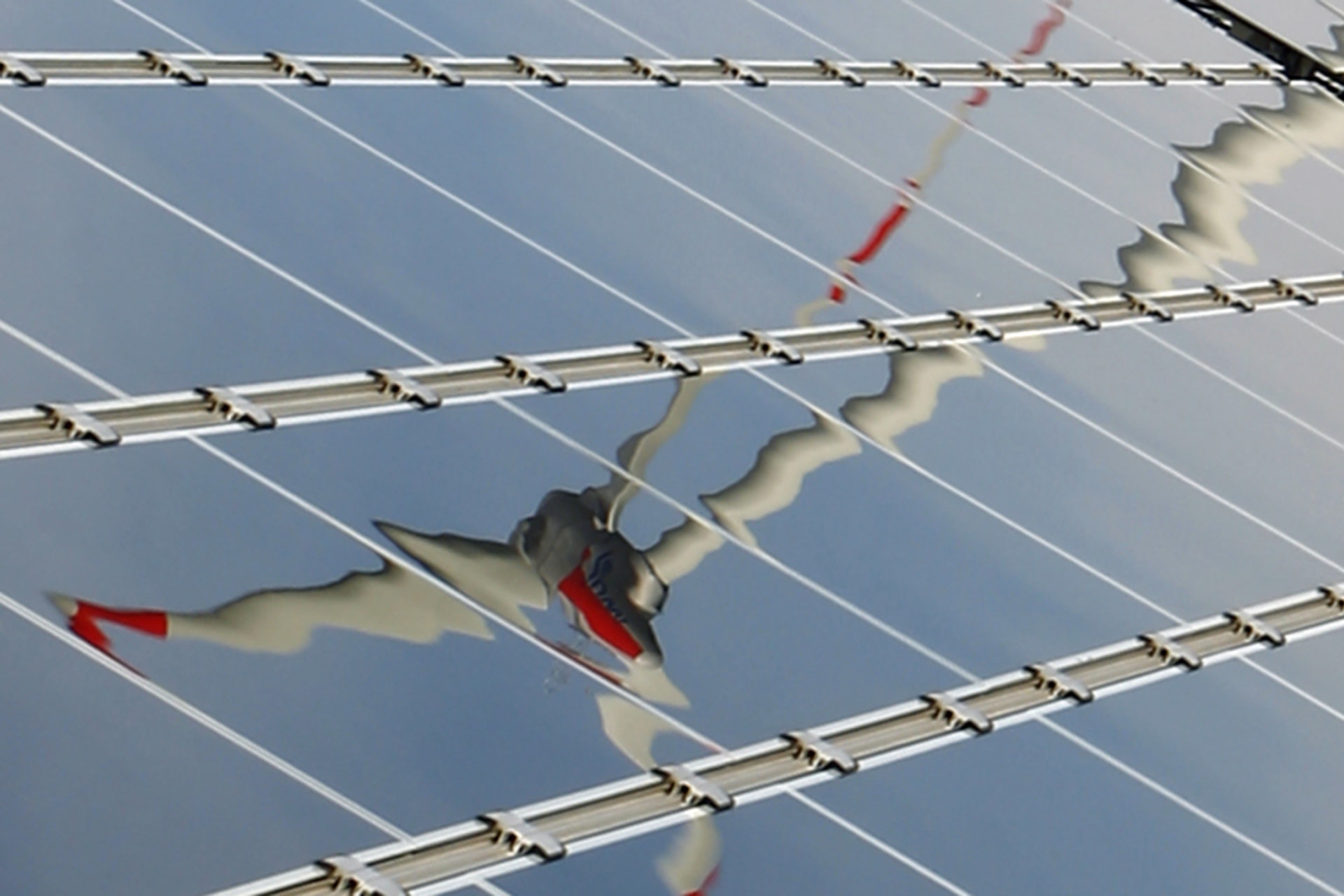 <p>A power-generating wind turbine is reflected in solar panels near Mainz, Germany, on March 10, 2010.</p>
