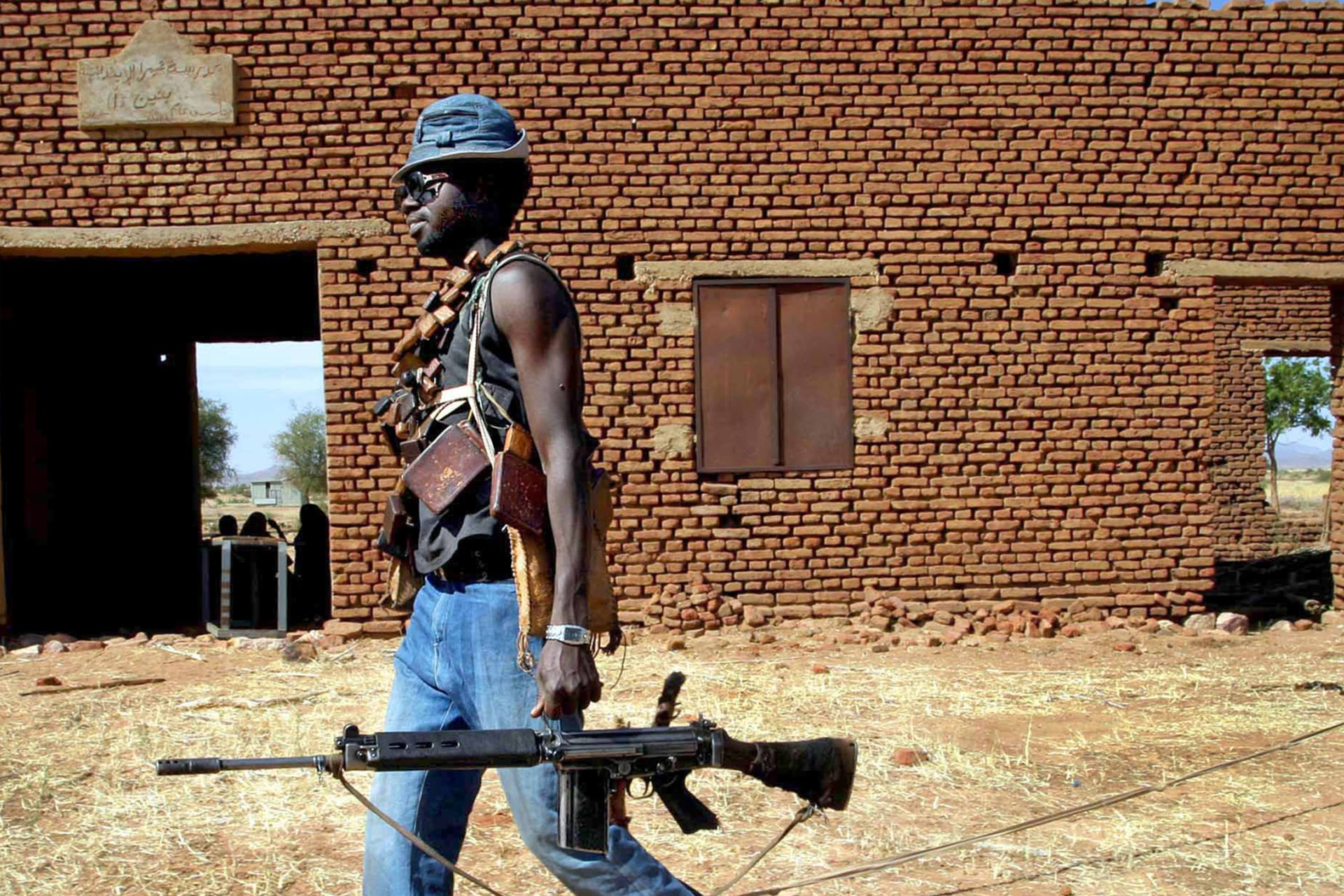 <p>A Sudan Liberation Army (SLA) rebel passes an abandoned building in the desert west of El Fasher, the capital of North Darfur state, on November 8, 2004.</p>
