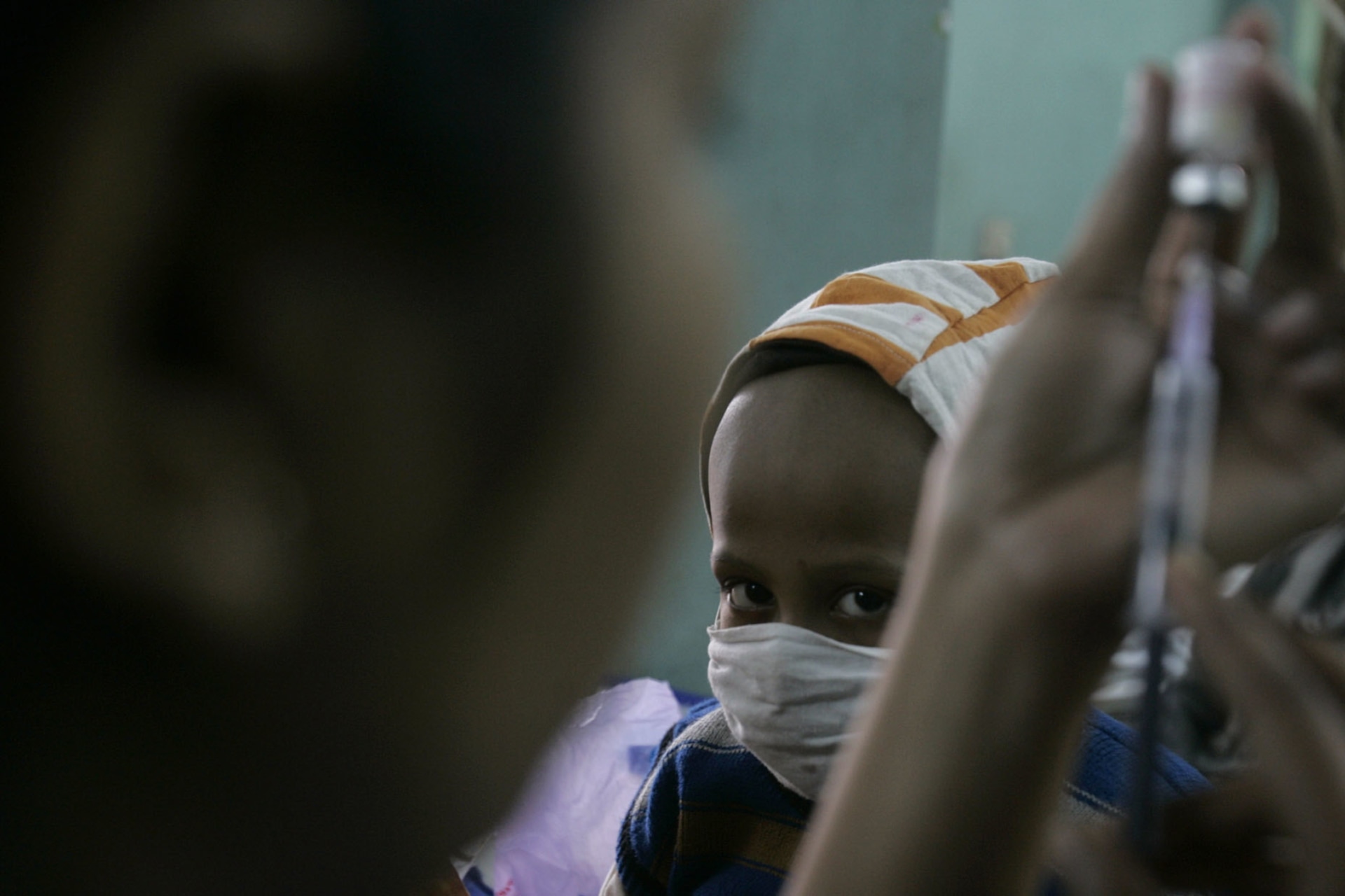 <p>A nurse prepares an injection for five-year-old cancer patient Debadyuti Biswas (wearing mask) during her treatment at a hospital in the eastern Indian city of Kolkata on World Cancer Day on February 4, 2009.</p>
