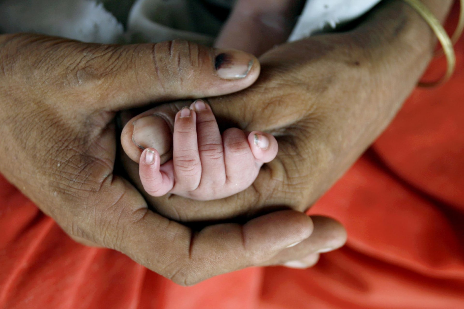 <p>Bismillah holds the hand of her newly born child as she feeds her in Akhera village in the northern Indian state of Haryana on July 4, 2007.</p>