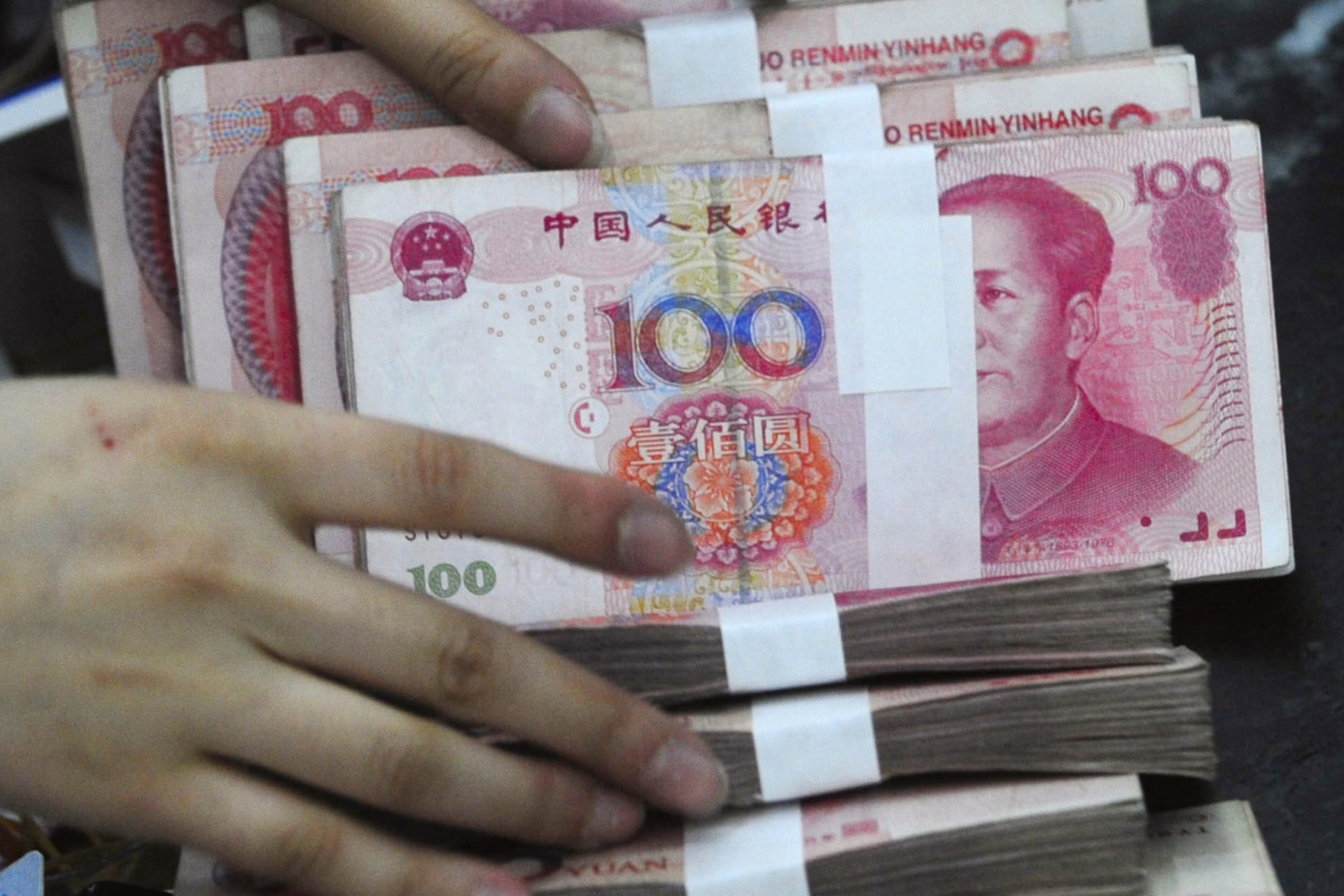 <p>An employee prepares to hand over yuan banknotes to a customer at a branch of Bank of China in Hefei, Anhui province, on March 23, 2010.</p>