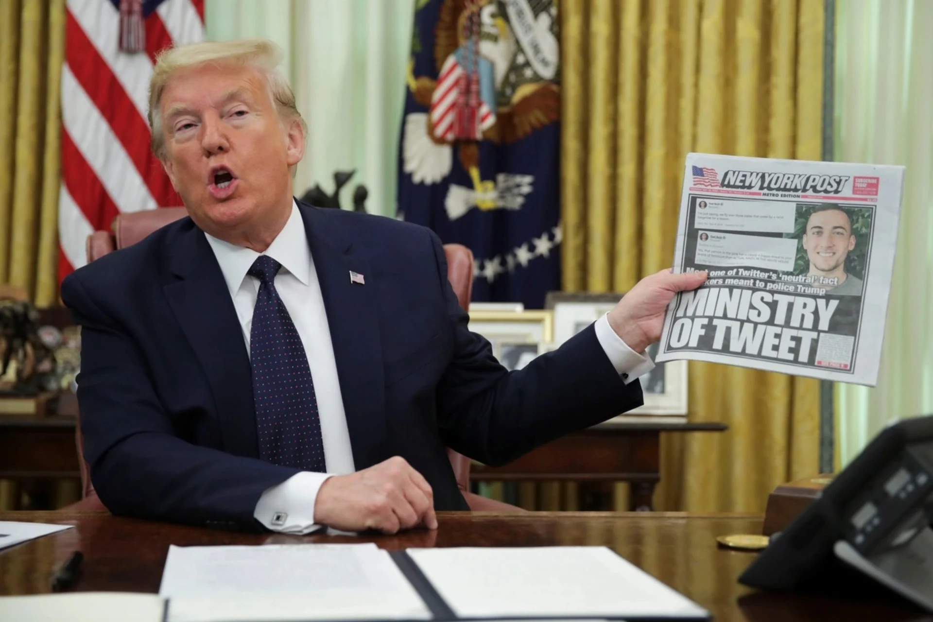 U.S. President Donald Trump holds up a front page of the New York Post. 
