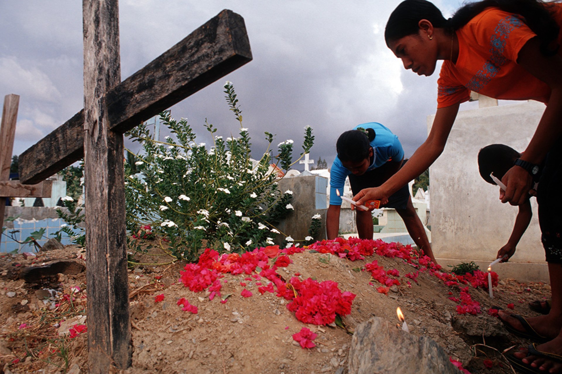 Children place flowers and candles on the grave of their father in the Santa Cruz cemetery, the site of a massacre by the Indonesian Army in 1991.