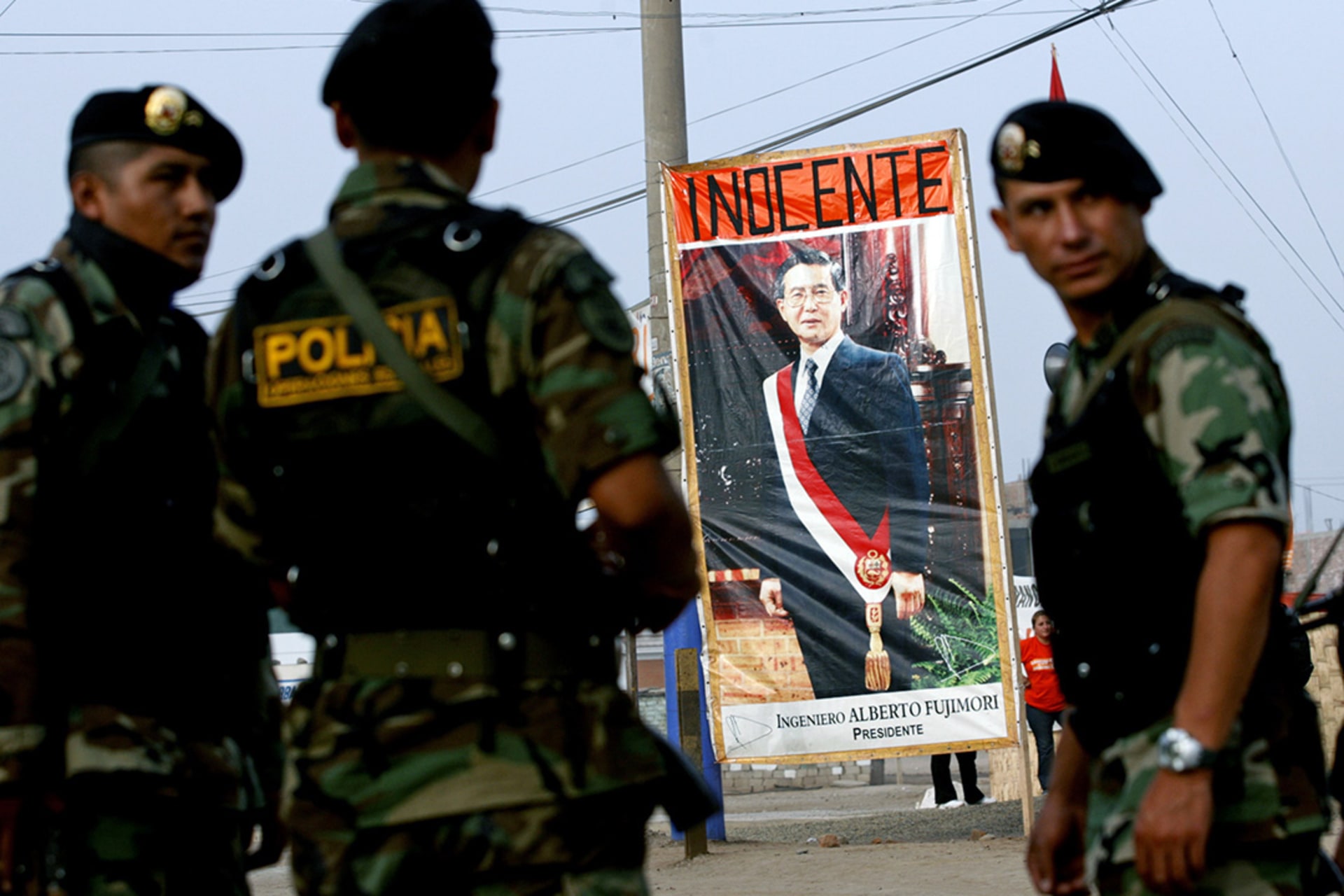 Police stand next to a poster of former Peruvian President Alberto Fujimori at the Special Police Headquarters in Lima before his trial begins. 
