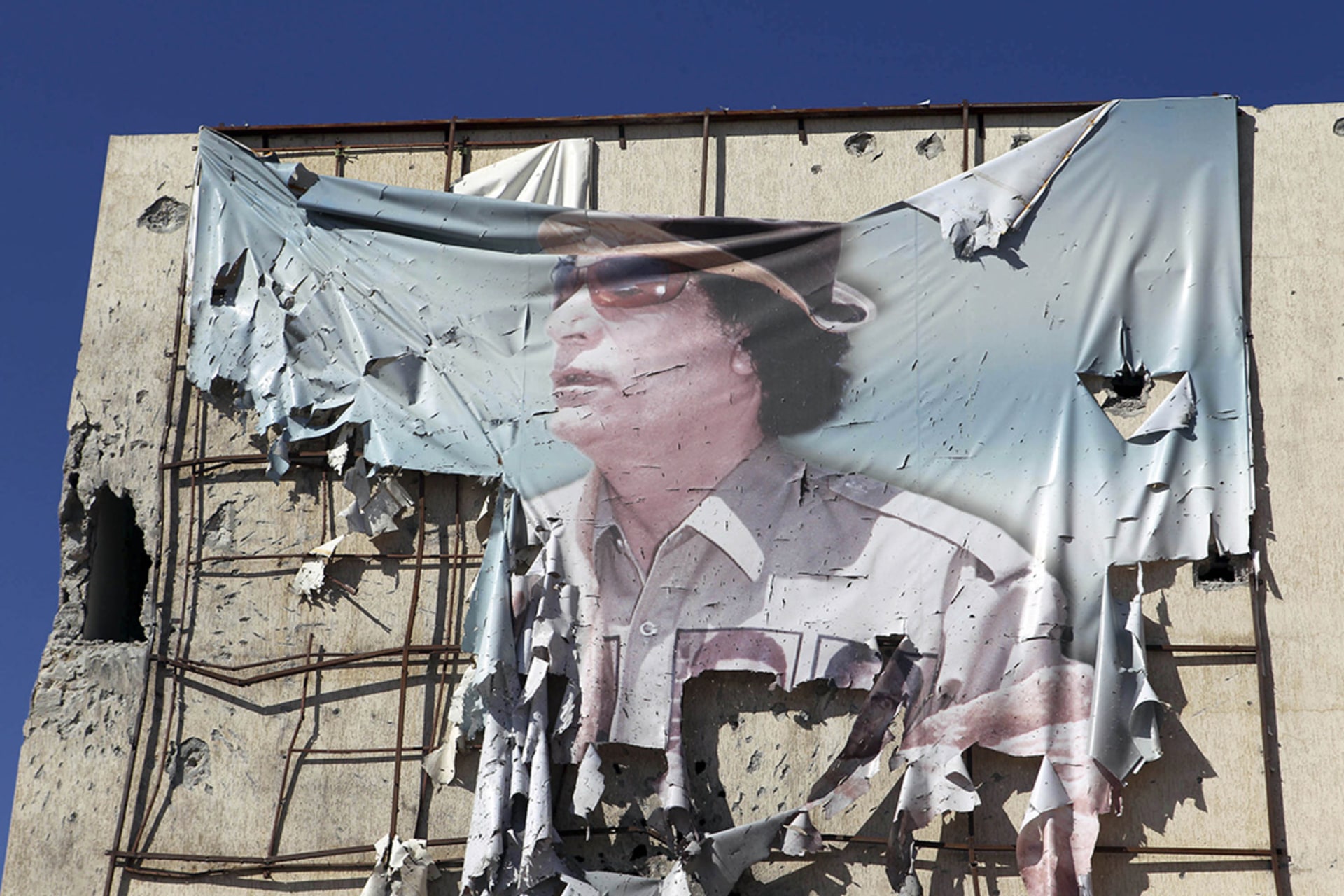 A torn banner showing Libyan leader Muammar al-Qaddafi is seen on a building during clashes in Sirte in 2011.