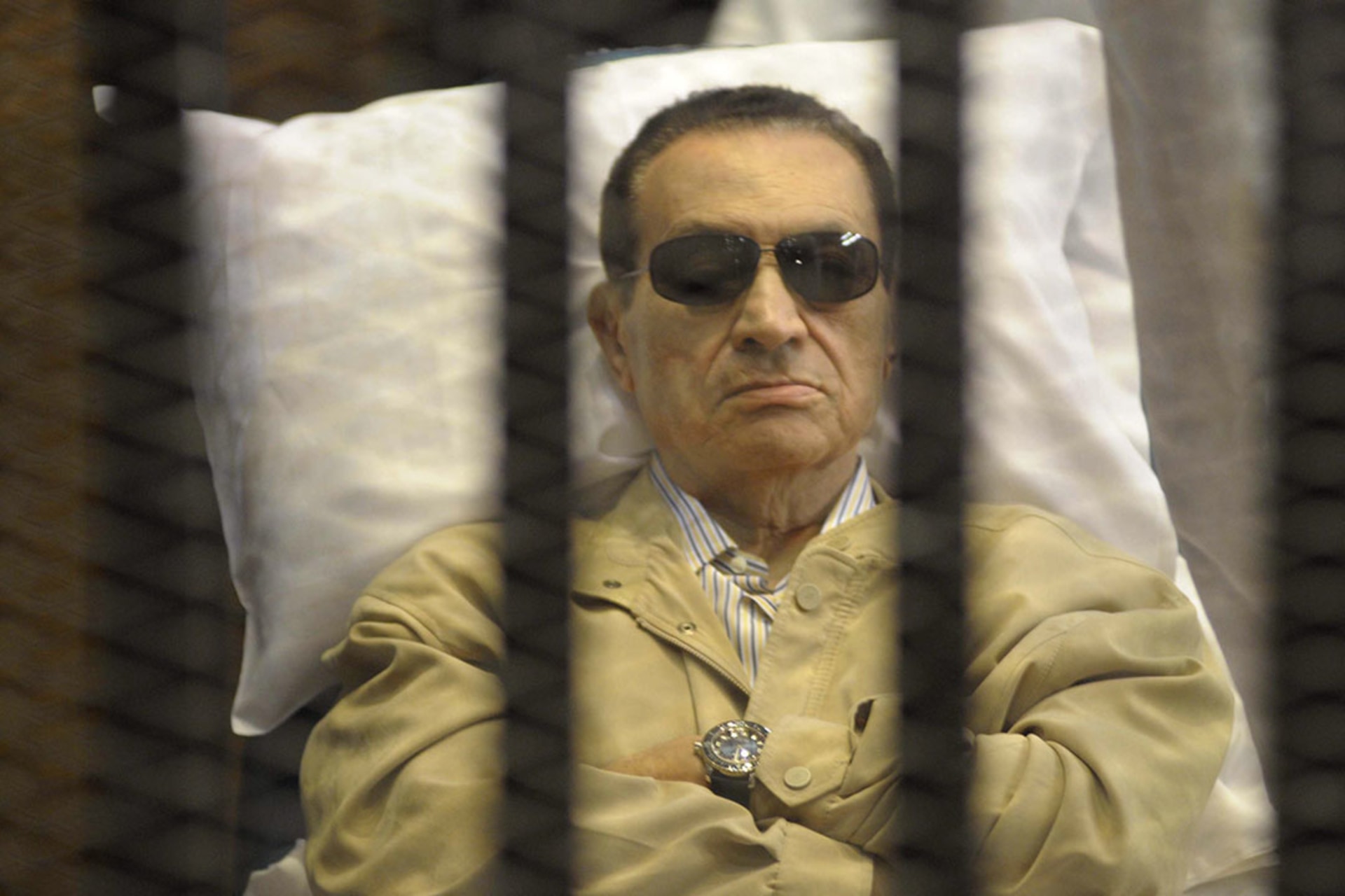 Former Egyptian President Hosni Mubarak sits in a cage in a Cairo courtroom.
