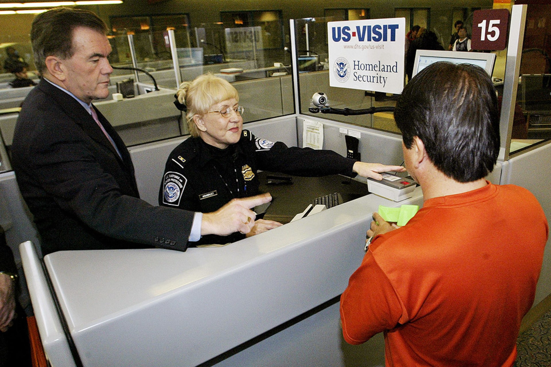 U.S. Homeland Security Secretary Tom Ridge assists a foreign airline passenger getting fingerprinted at an airport security checkpoint. Tami Chappelle/Reuters