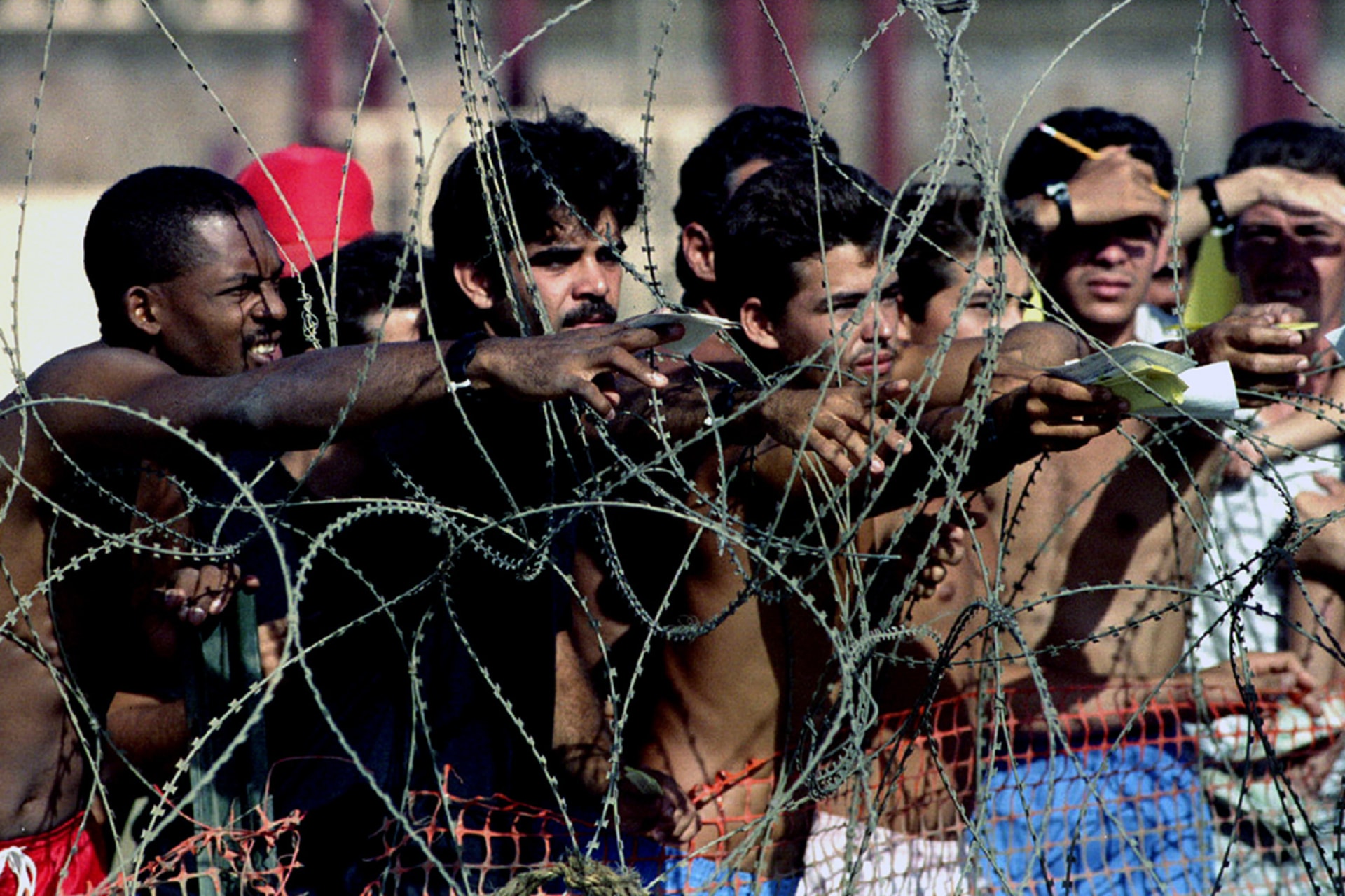 Cuban refugees being held at Guantanamo Naval Base try to pass notes through concertina wire on August 27, 1994.