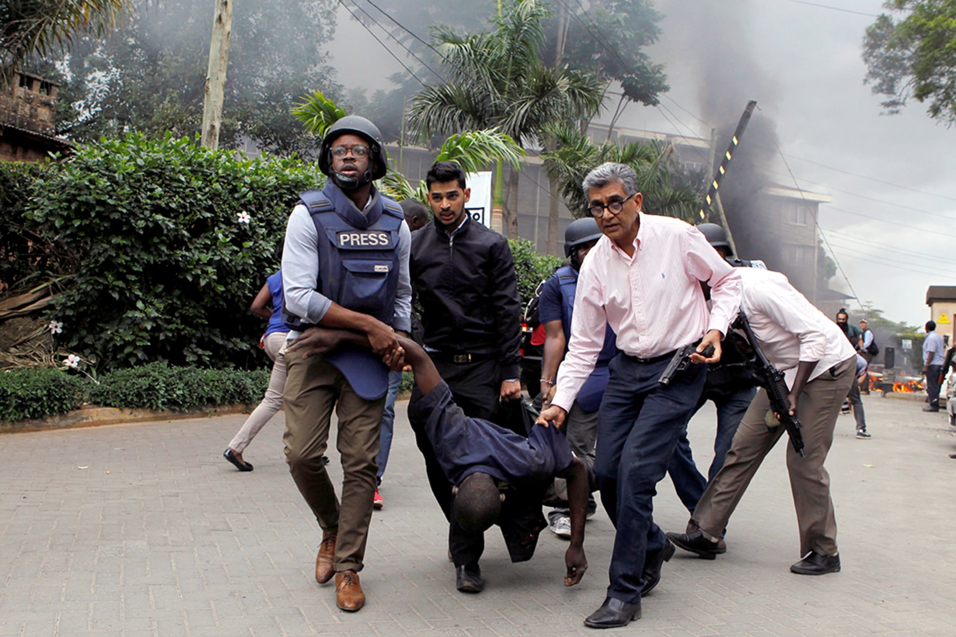 Rescuers and journalists evacuate an injured man from the Dusit hotel compound in Nairobi, Kenya. 
