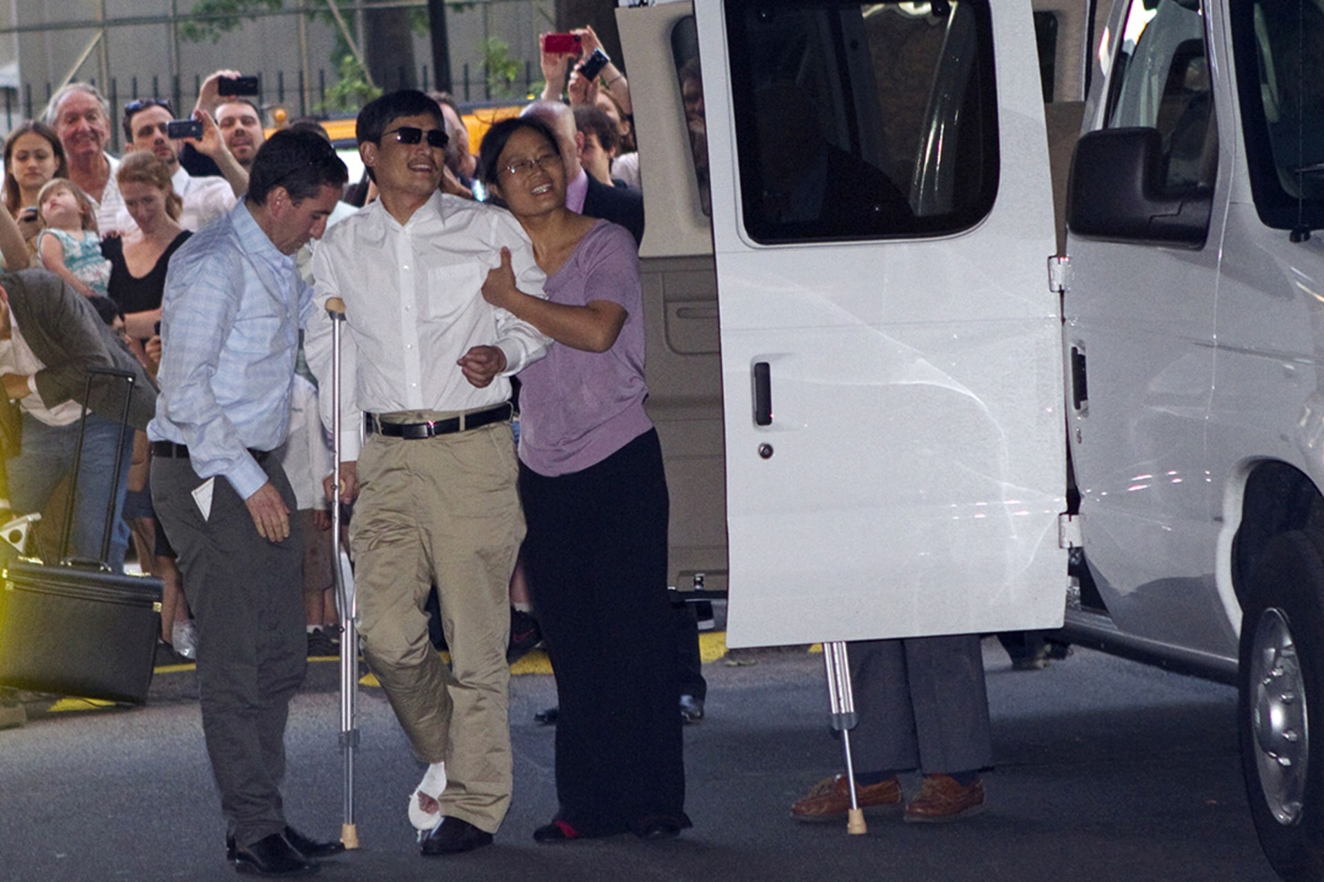 Activist Chen Guangcheng is helped by his wife as he arrives in New York.
