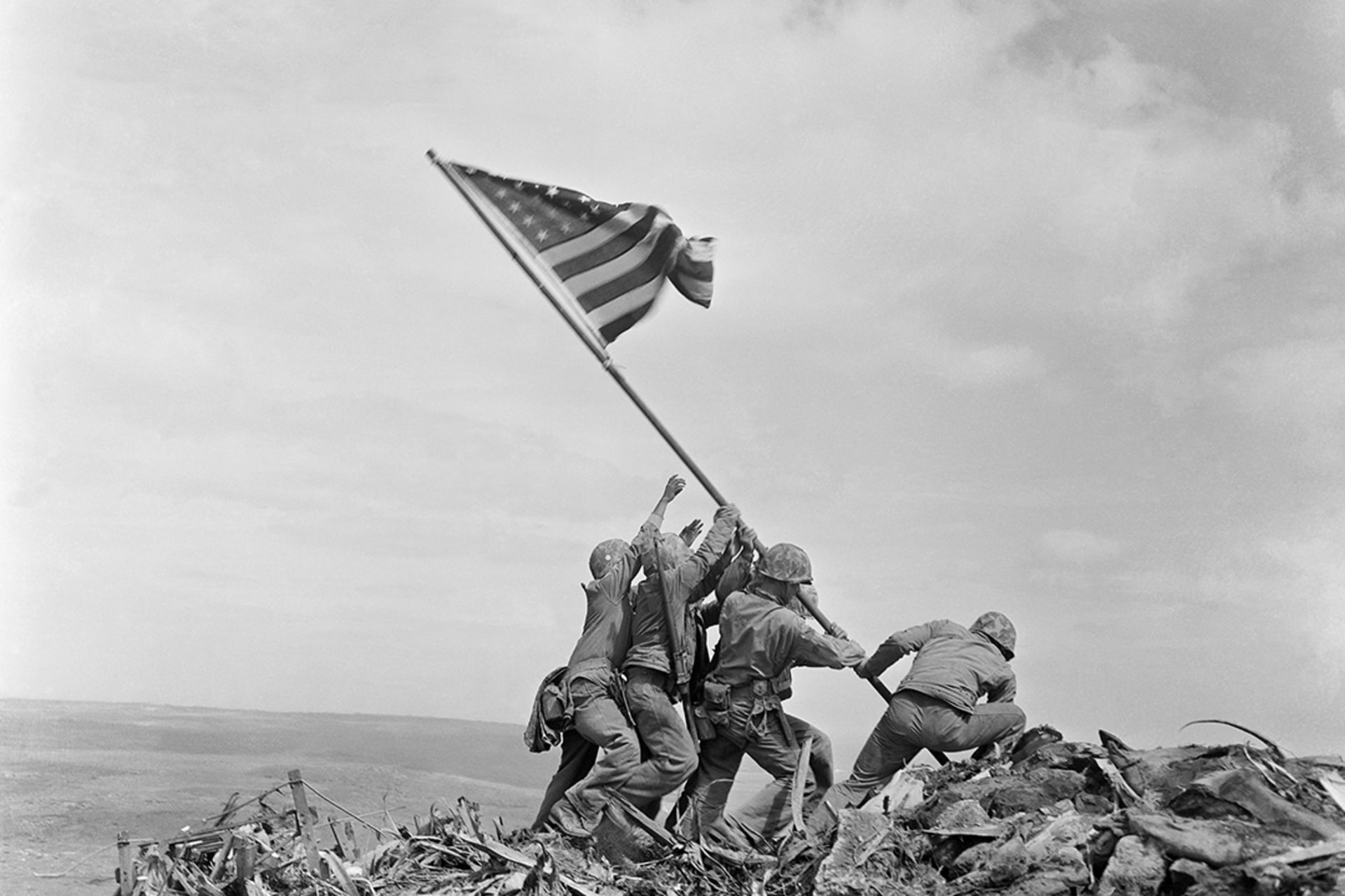 U.S. Marines raise a U.S. flag atop Mount Suribachi, Iwo Jima. 
